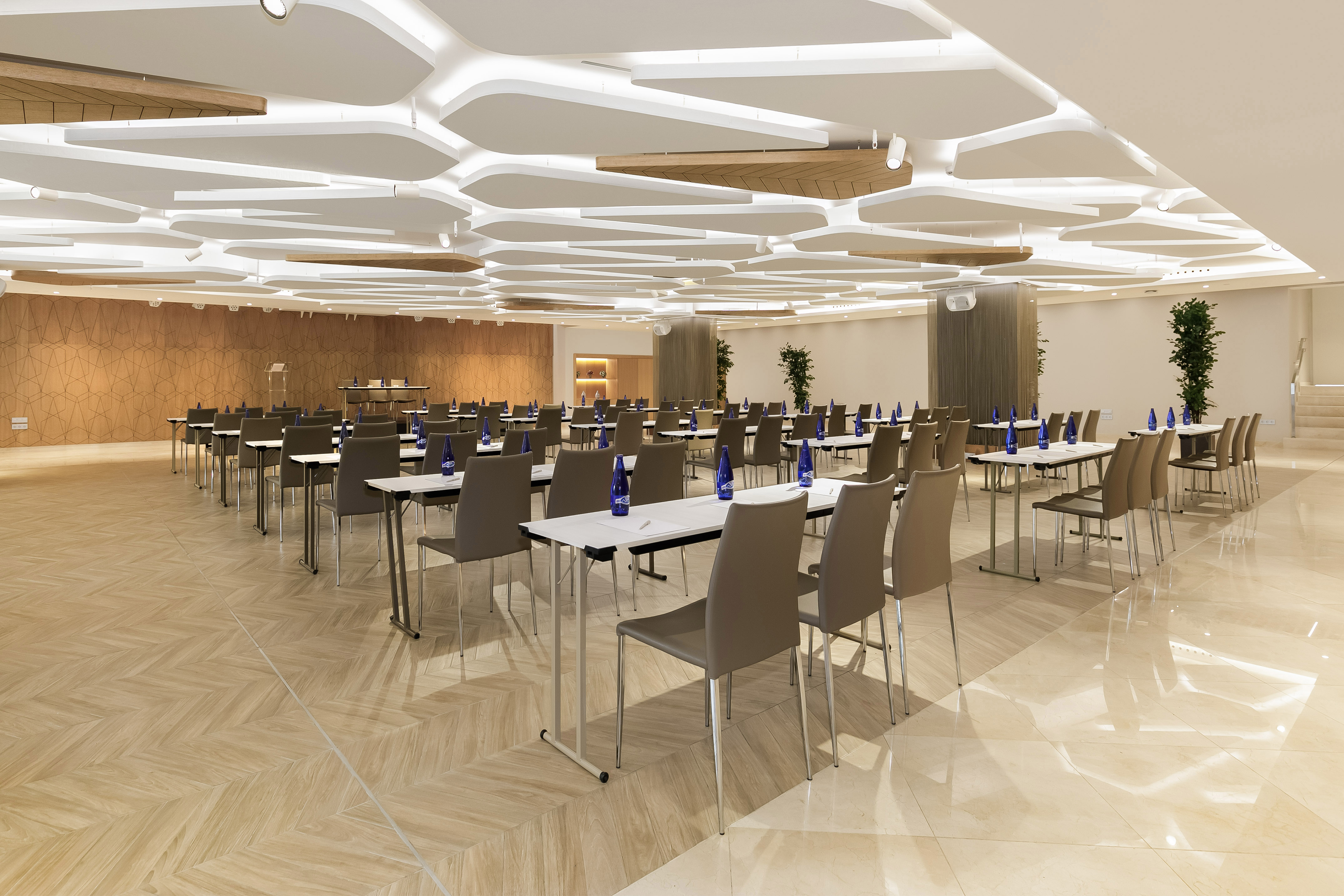Modern conference room with tables, chairs, and a distinctive wavy ceiling design.