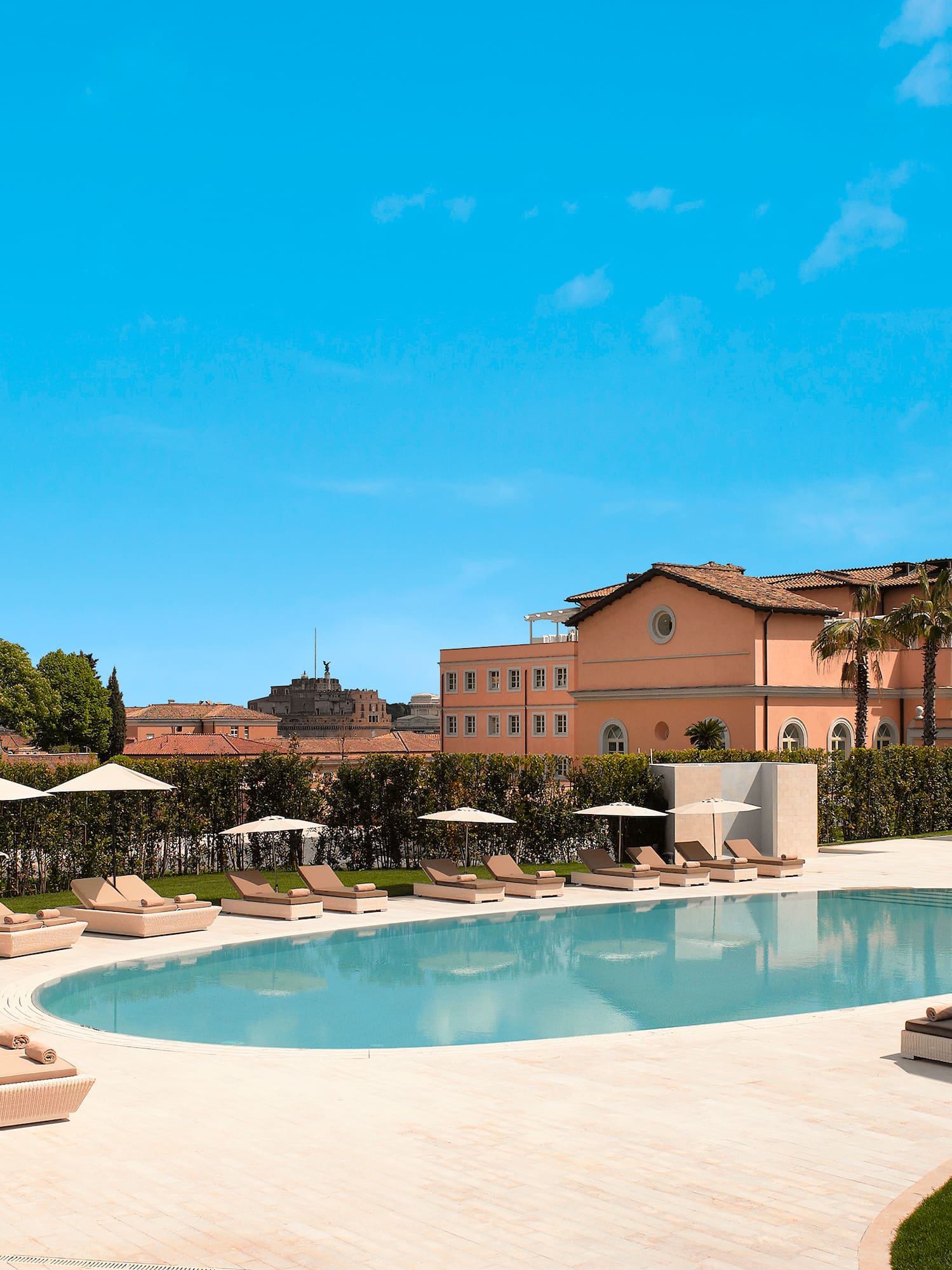 a pool with lounge chairs and umbrellas in front of a building