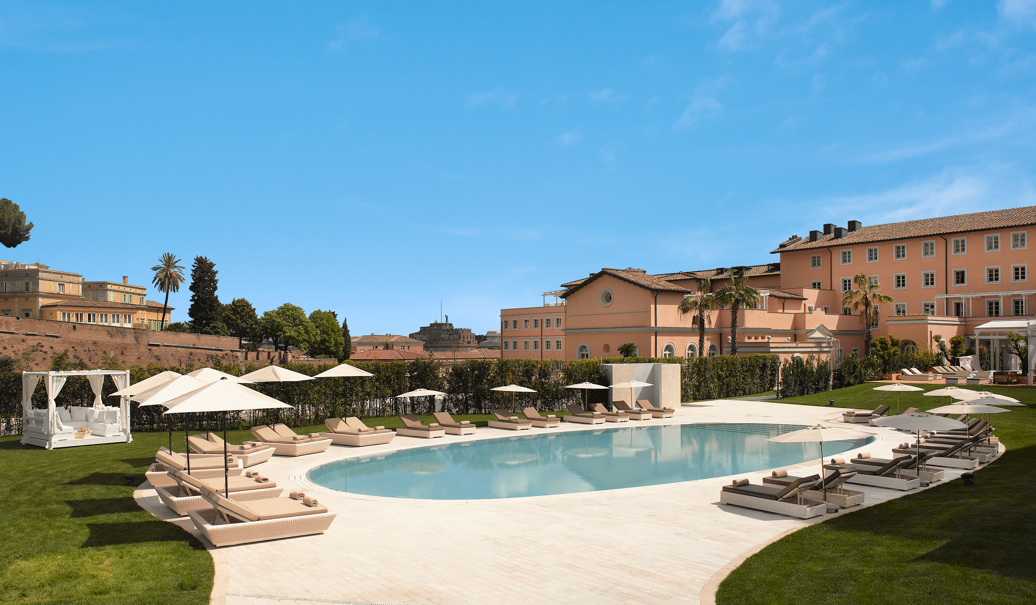 Rome resort pool with sun loungers, umbrellas, and historic buildings.