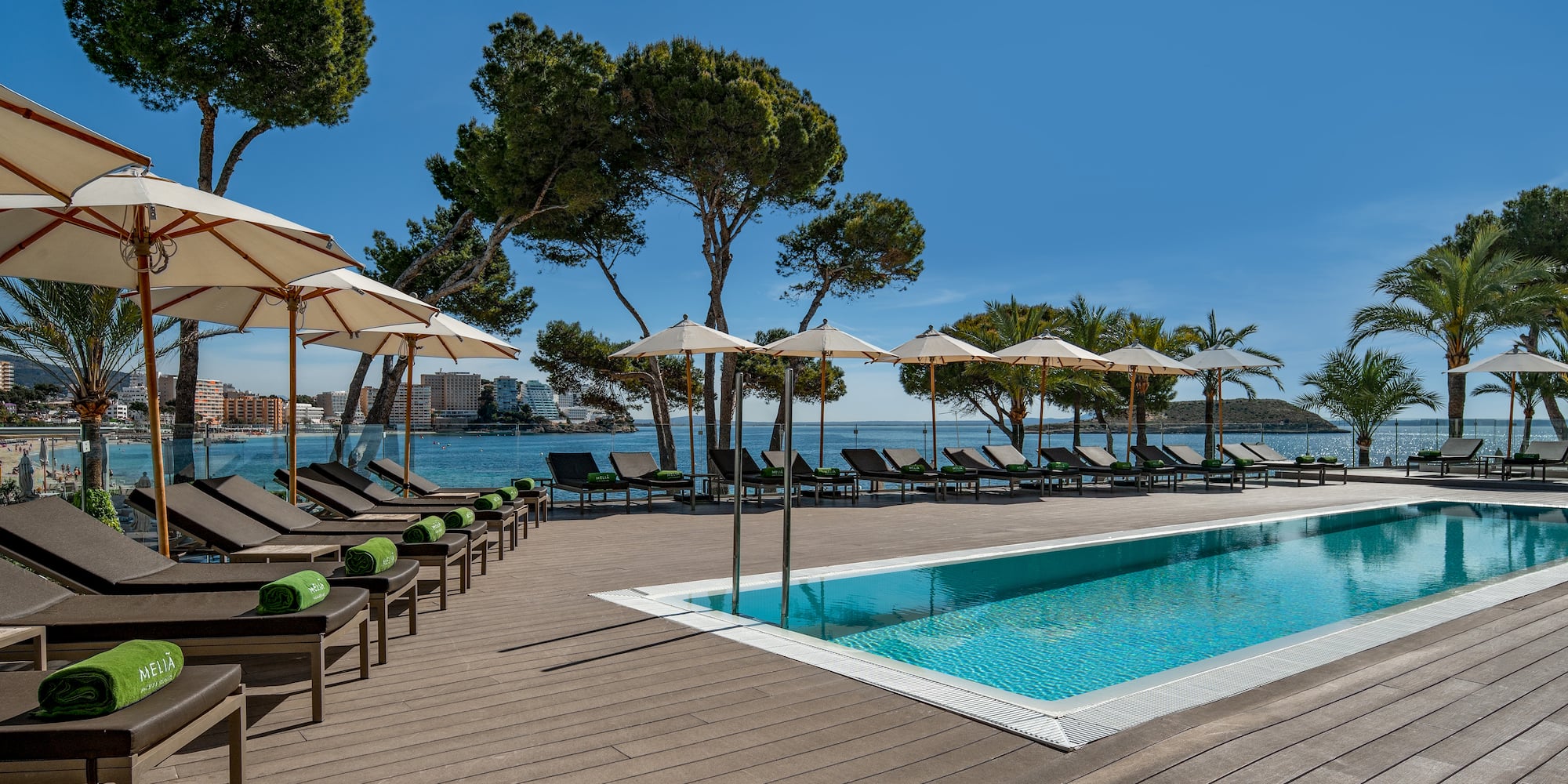 a pool with umbrellas and chairs by a body of water
