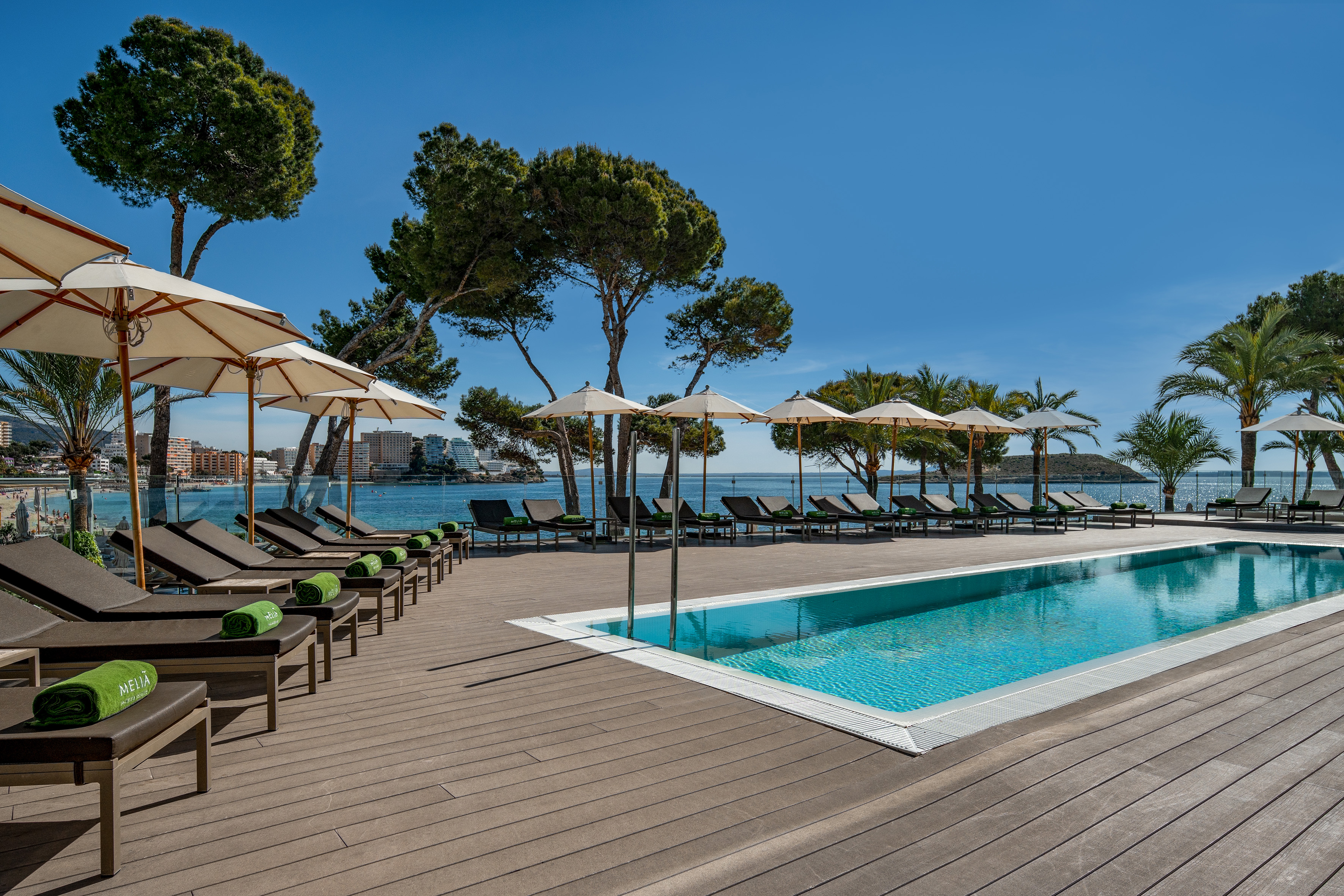 a pool with umbrellas and chairs by a body of water