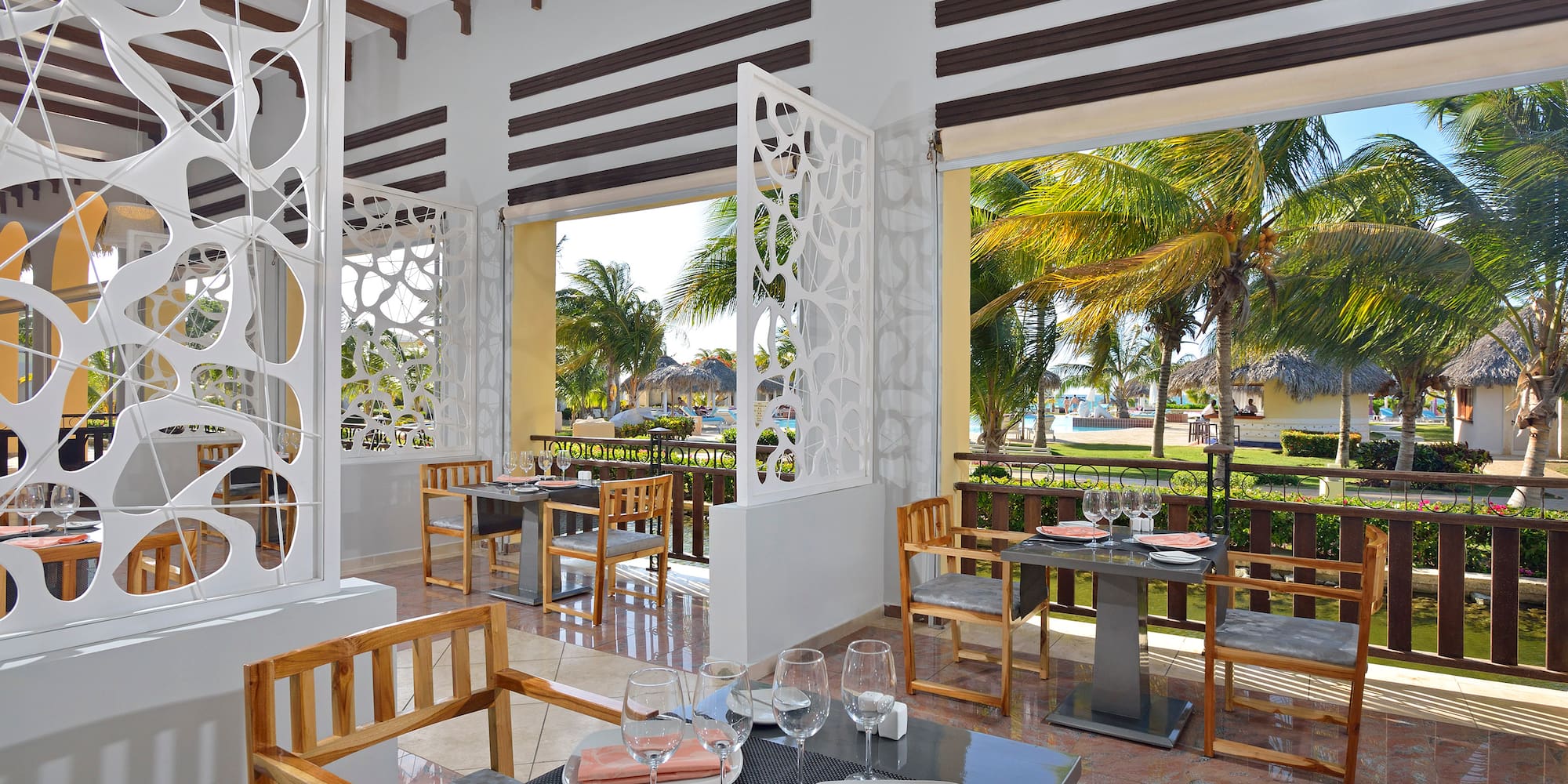 a room with tables and chairs and a view of the beach
