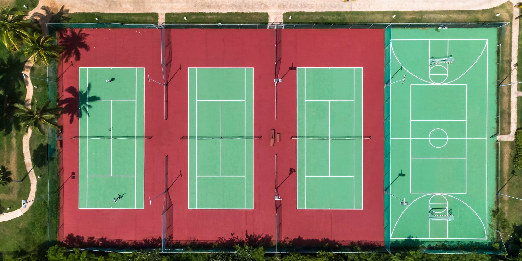 a tennis courts with trees and grass