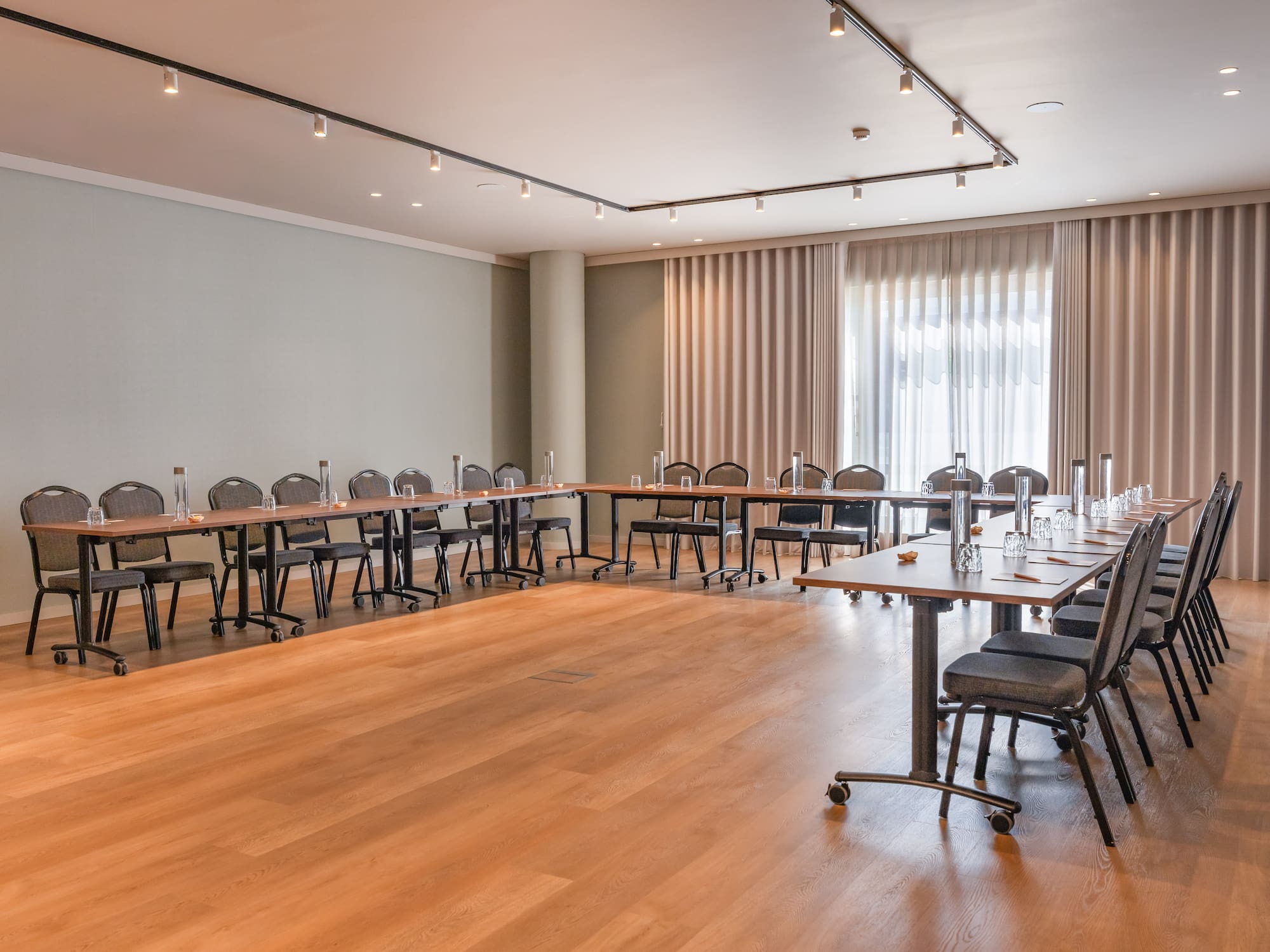 Bright, modern meeting room with U-shape table arrangement for corporate events.