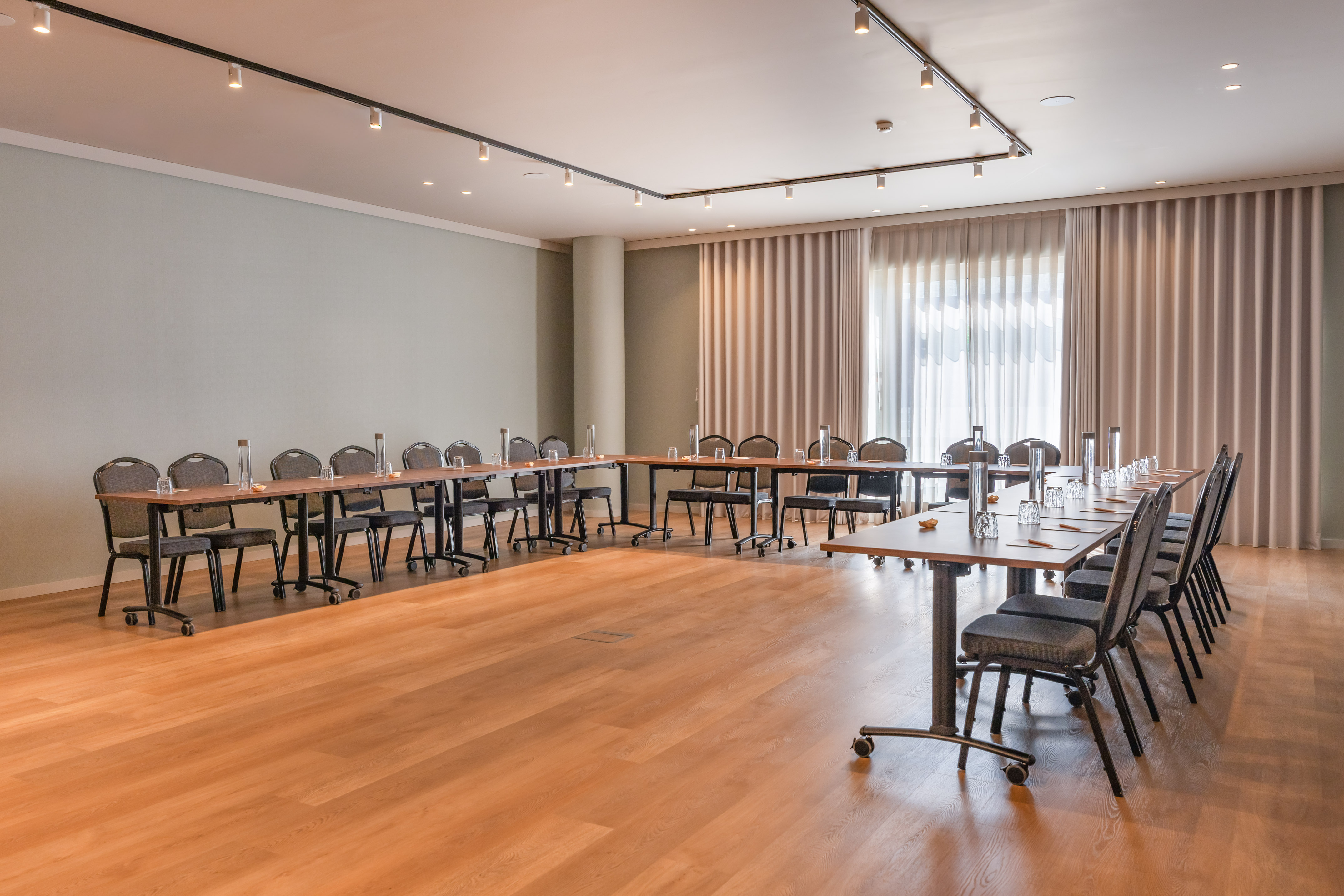Bright, modern meeting room with U-shape table arrangement for corporate events.