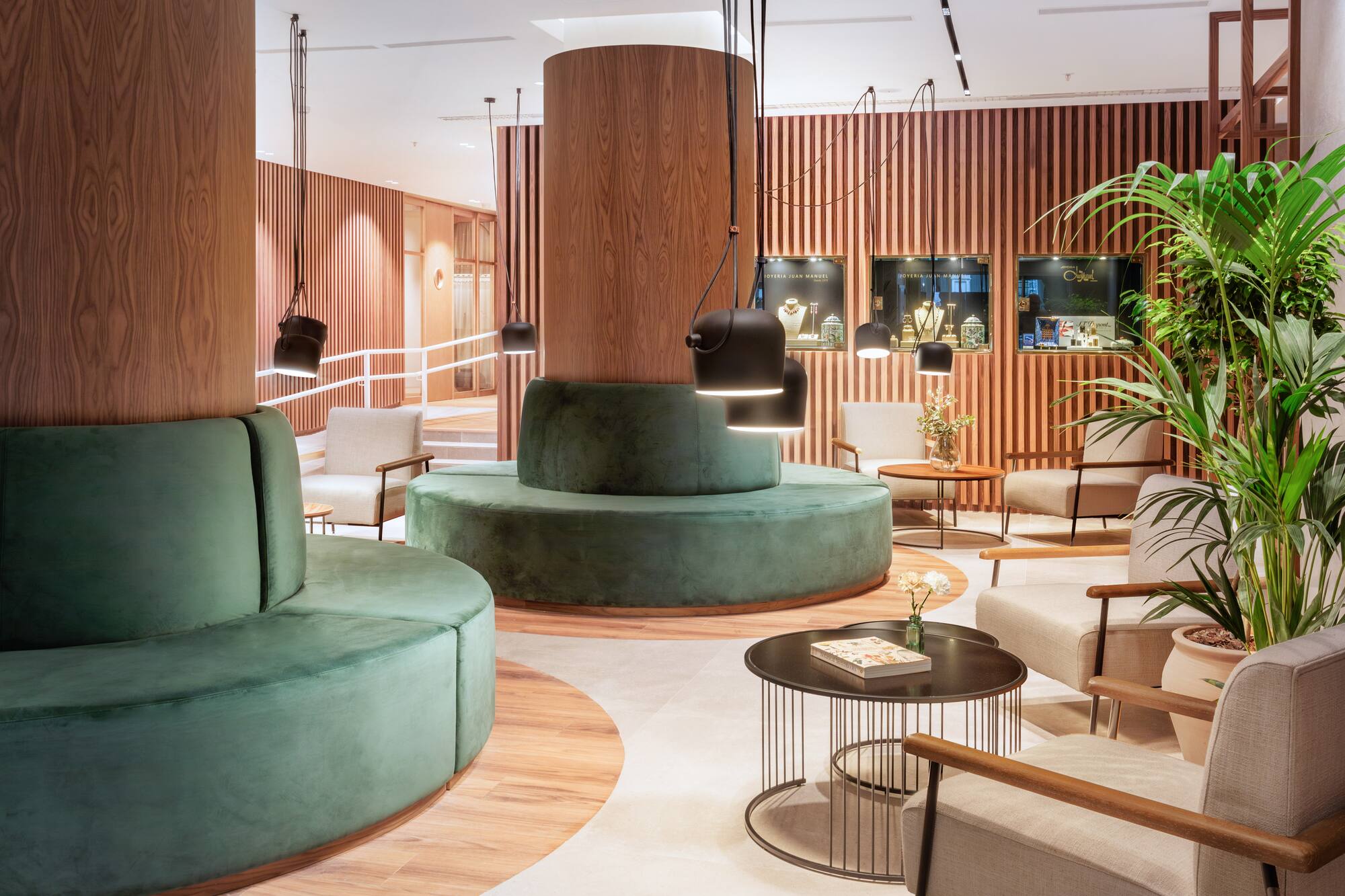 Modern lobby with green velvet sofas, wood paneling, and jewelry display cases.