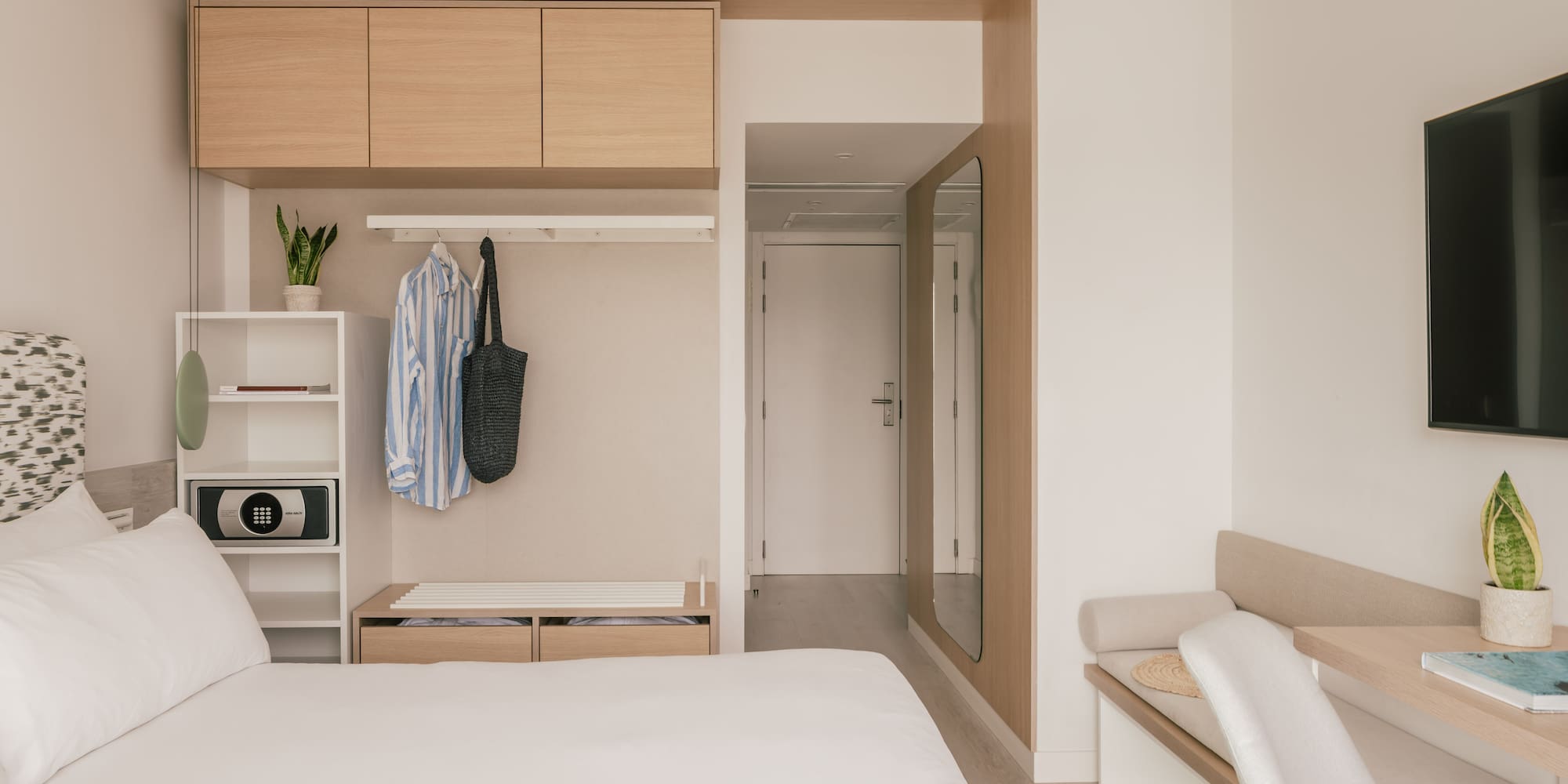 Habitación de hotel moderna y minimalista con cama, armario y escritorio.
