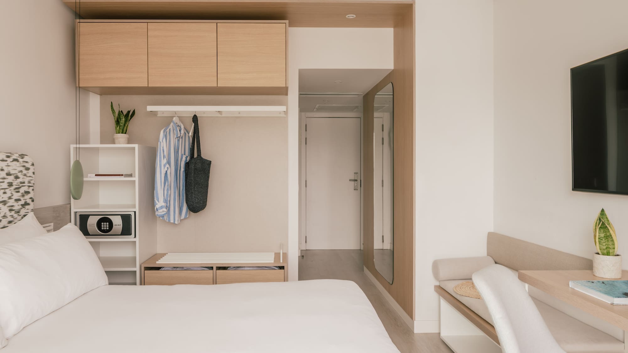 Habitación de hotel moderna y minimalista con cama, armario y escritorio.