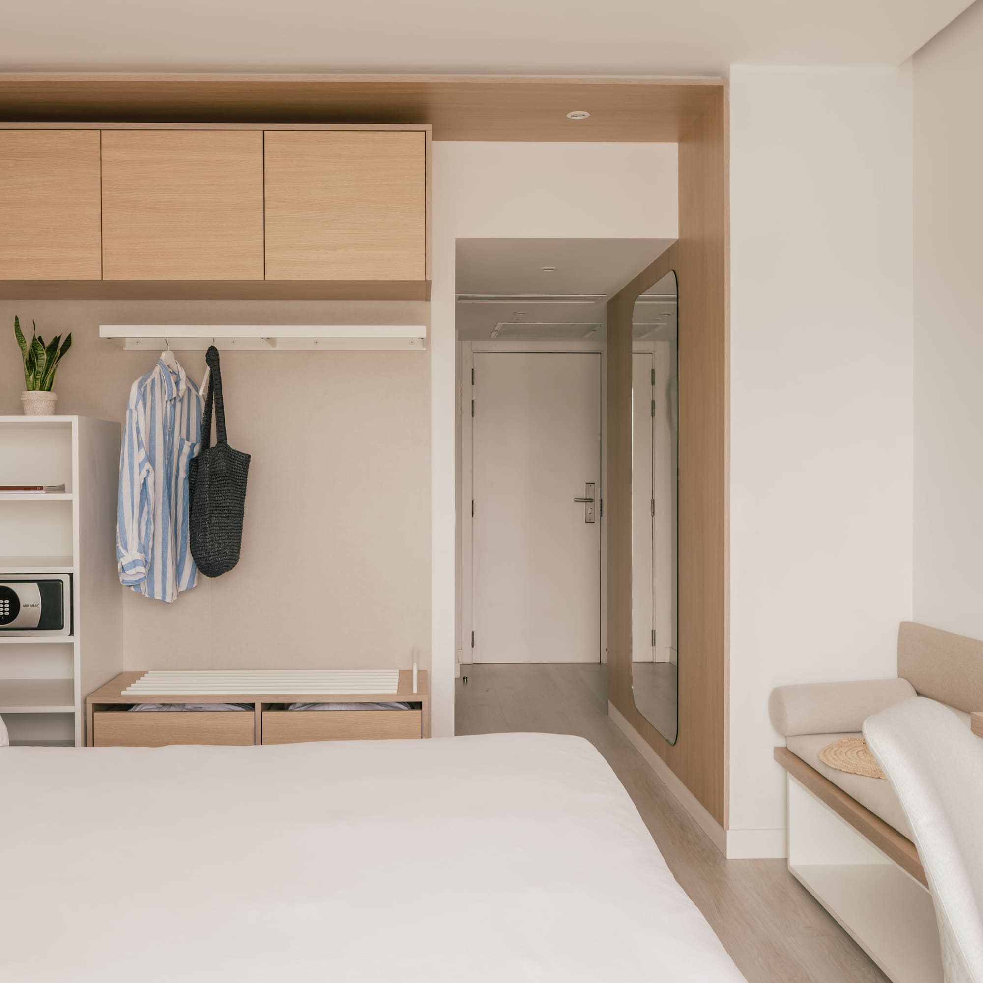 Habitación de hotel moderna y minimalista con cama, armario y escritorio.