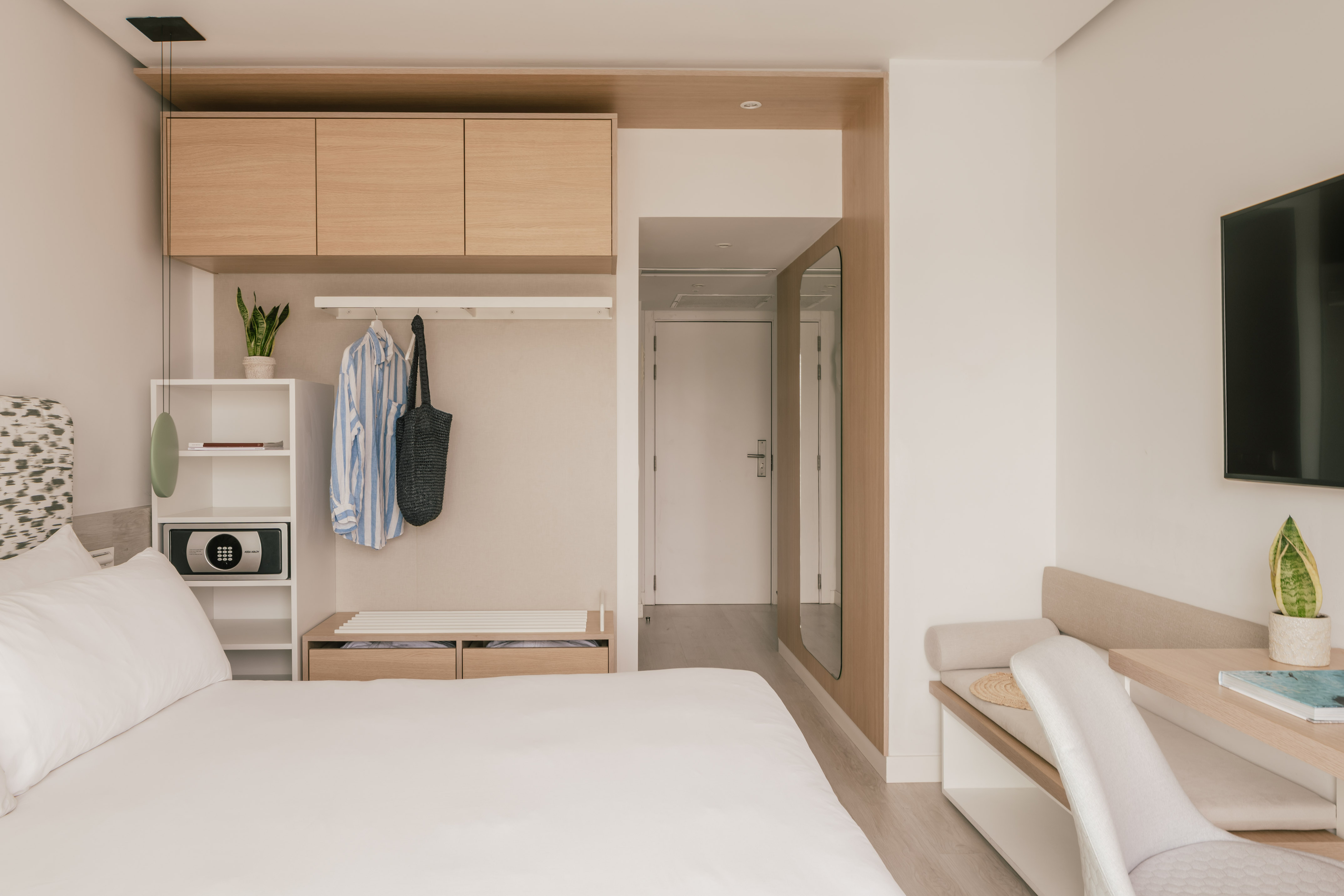 Habitación de hotel moderna y minimalista con cama, armario y escritorio.