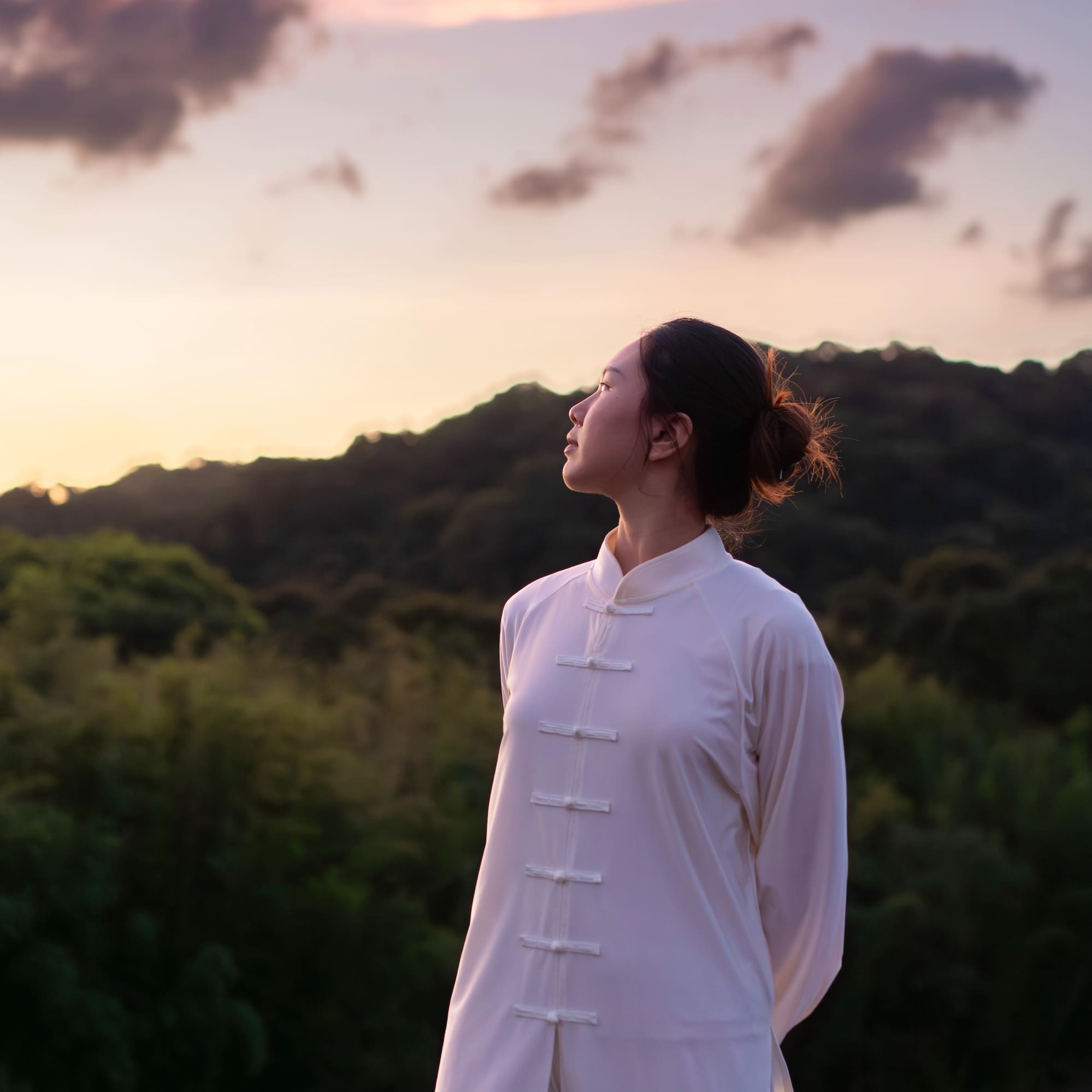 a woman in a white dress standing in front of trees