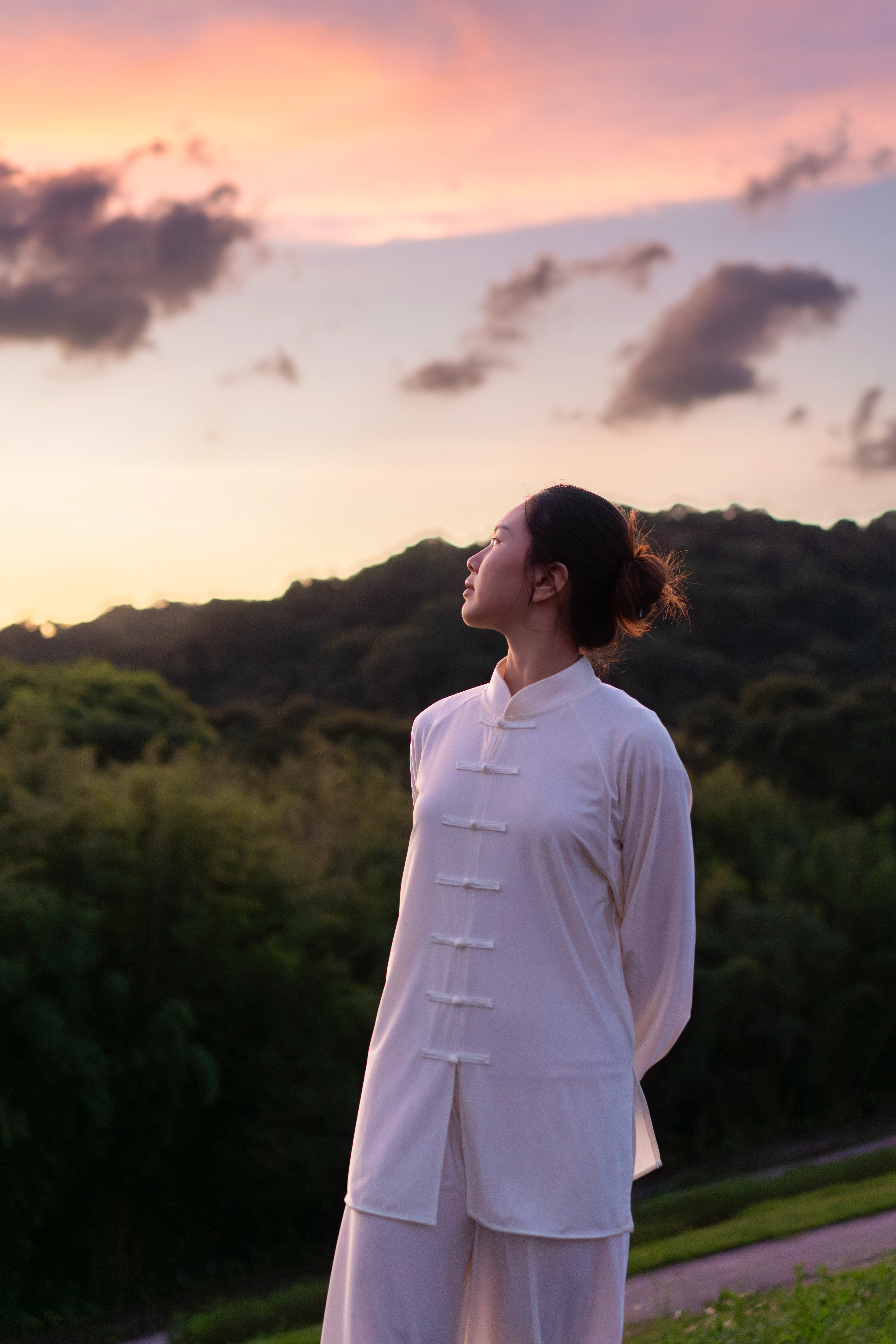 a woman in a white dress standing in front of trees