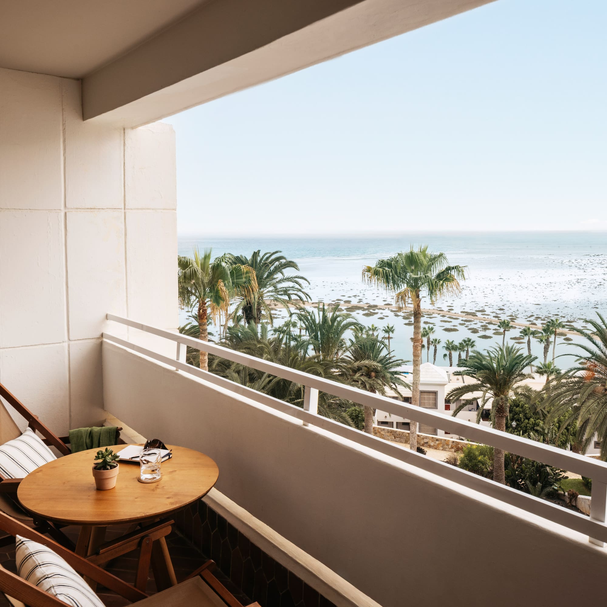 a balcony with a table and chairs and palm trees