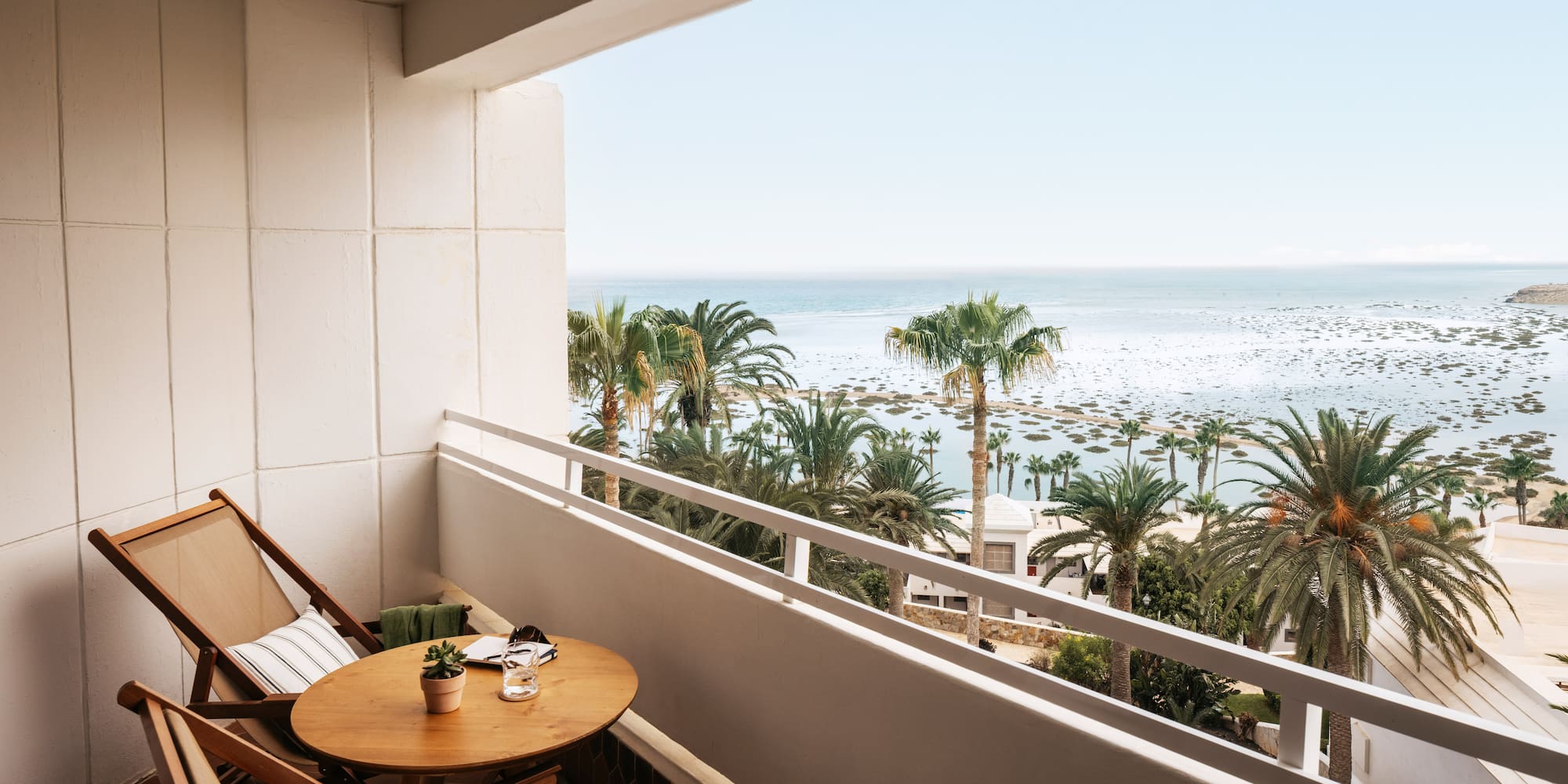 a balcony with a table and chairs and palm trees