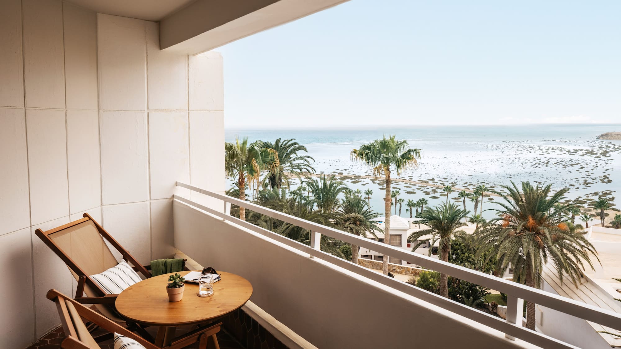a balcony with a table and chairs and palm trees