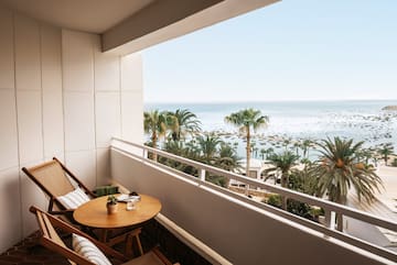 a balcony with a table and chairs and palm trees