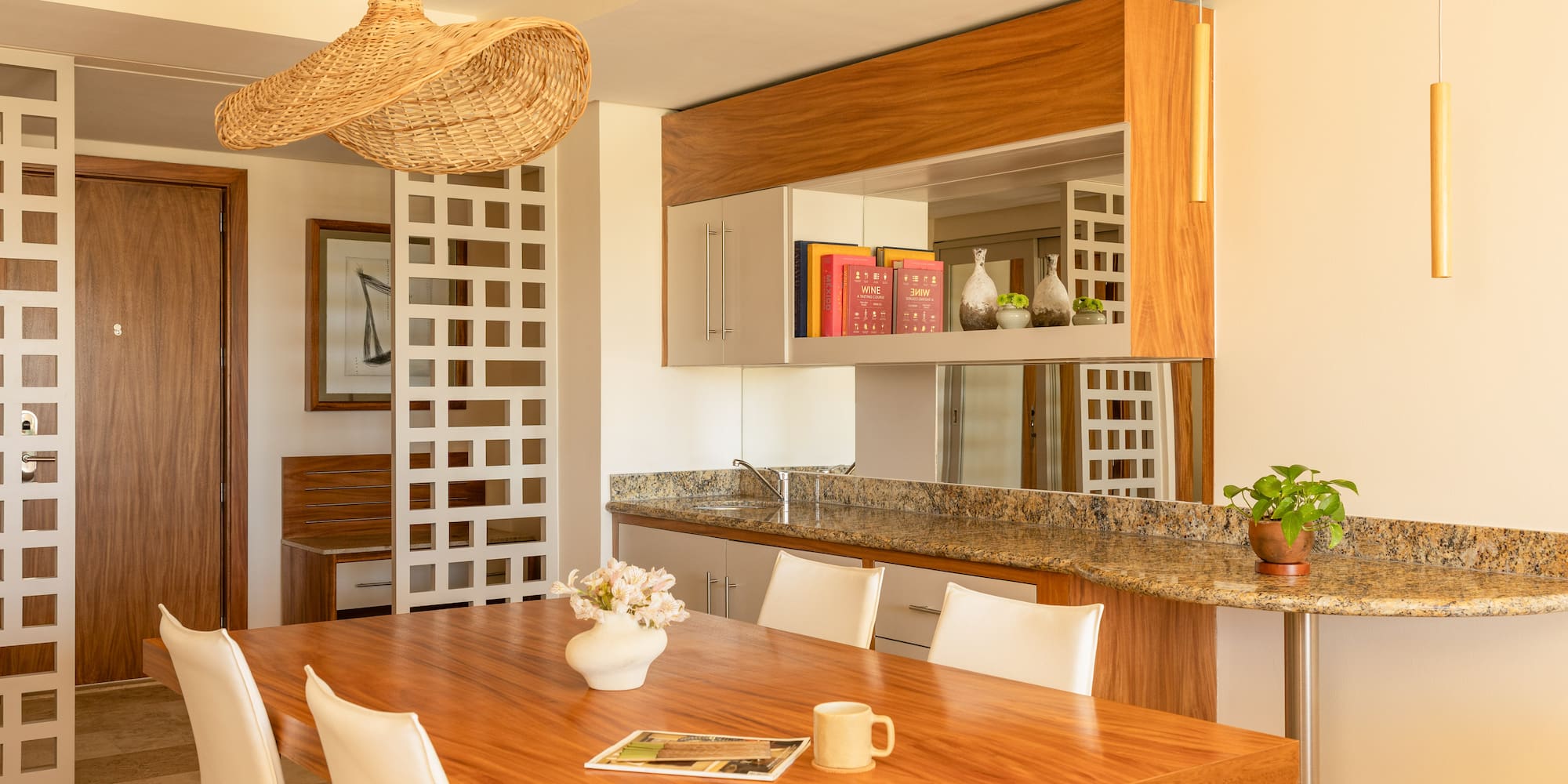 Modern dining room with wooden table, white chairs, and wicker pendant light.