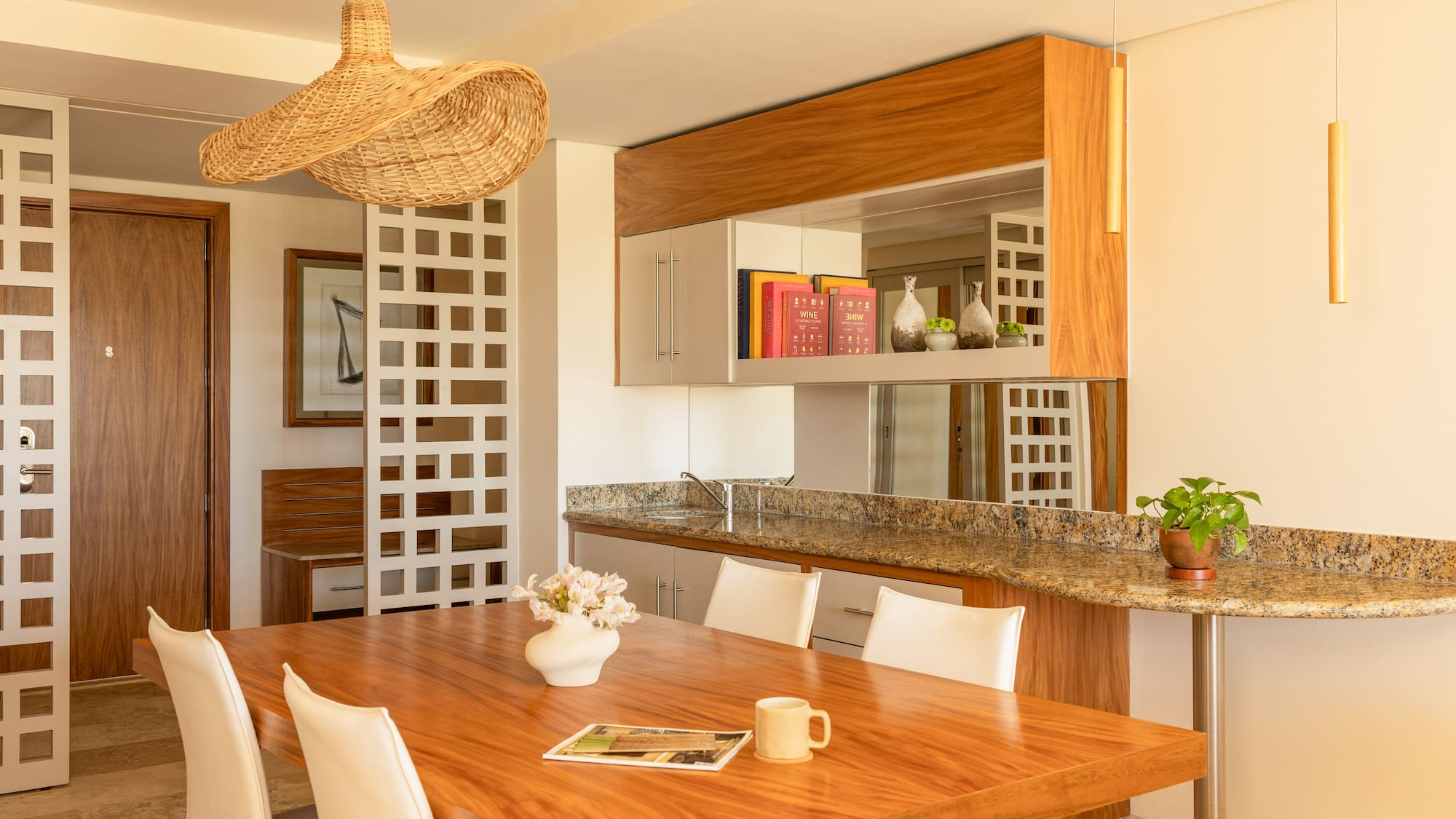 Modern dining room with wooden table, white chairs, and wicker pendant light.