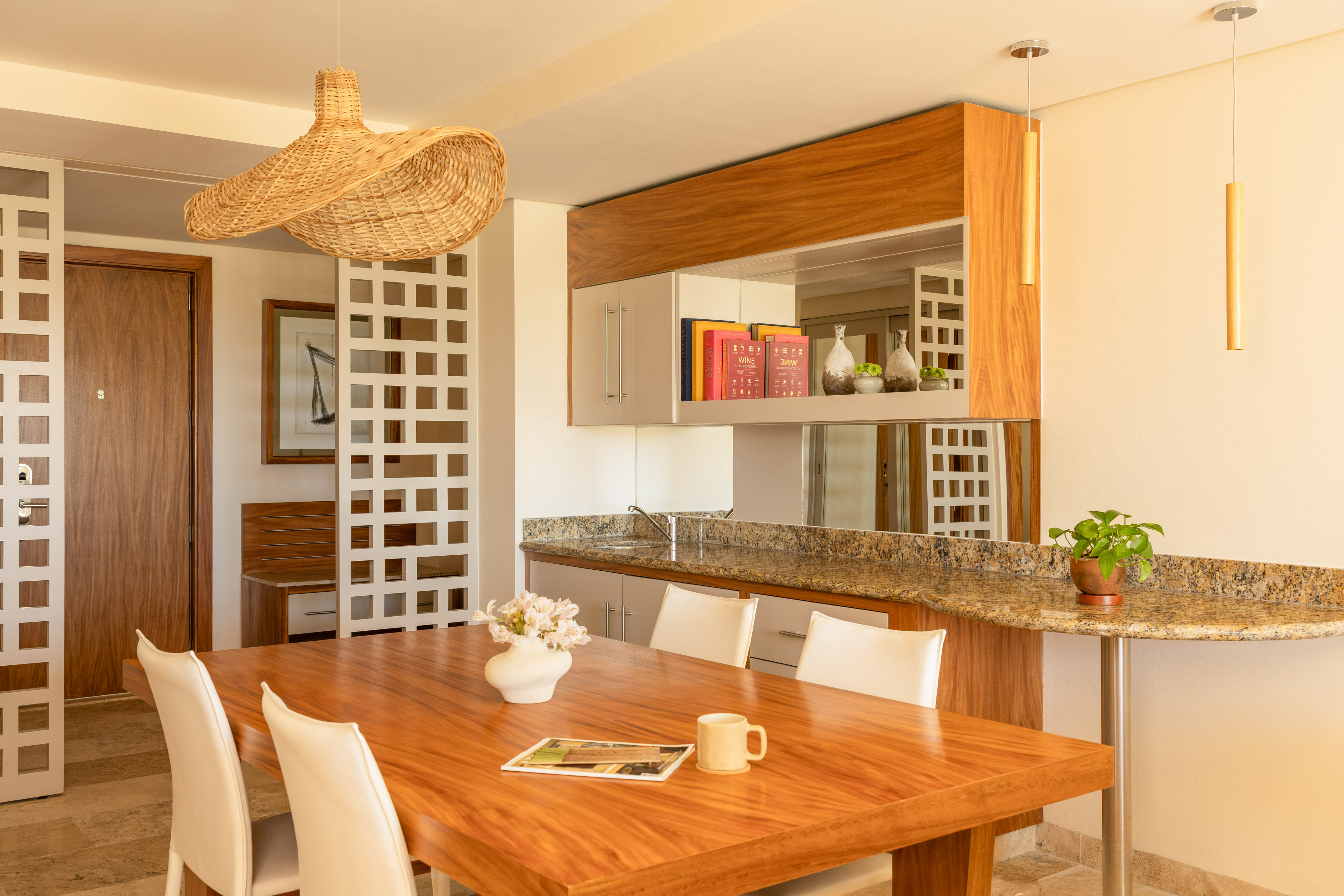 Modern dining room with wooden table, white chairs, and wicker pendant light.