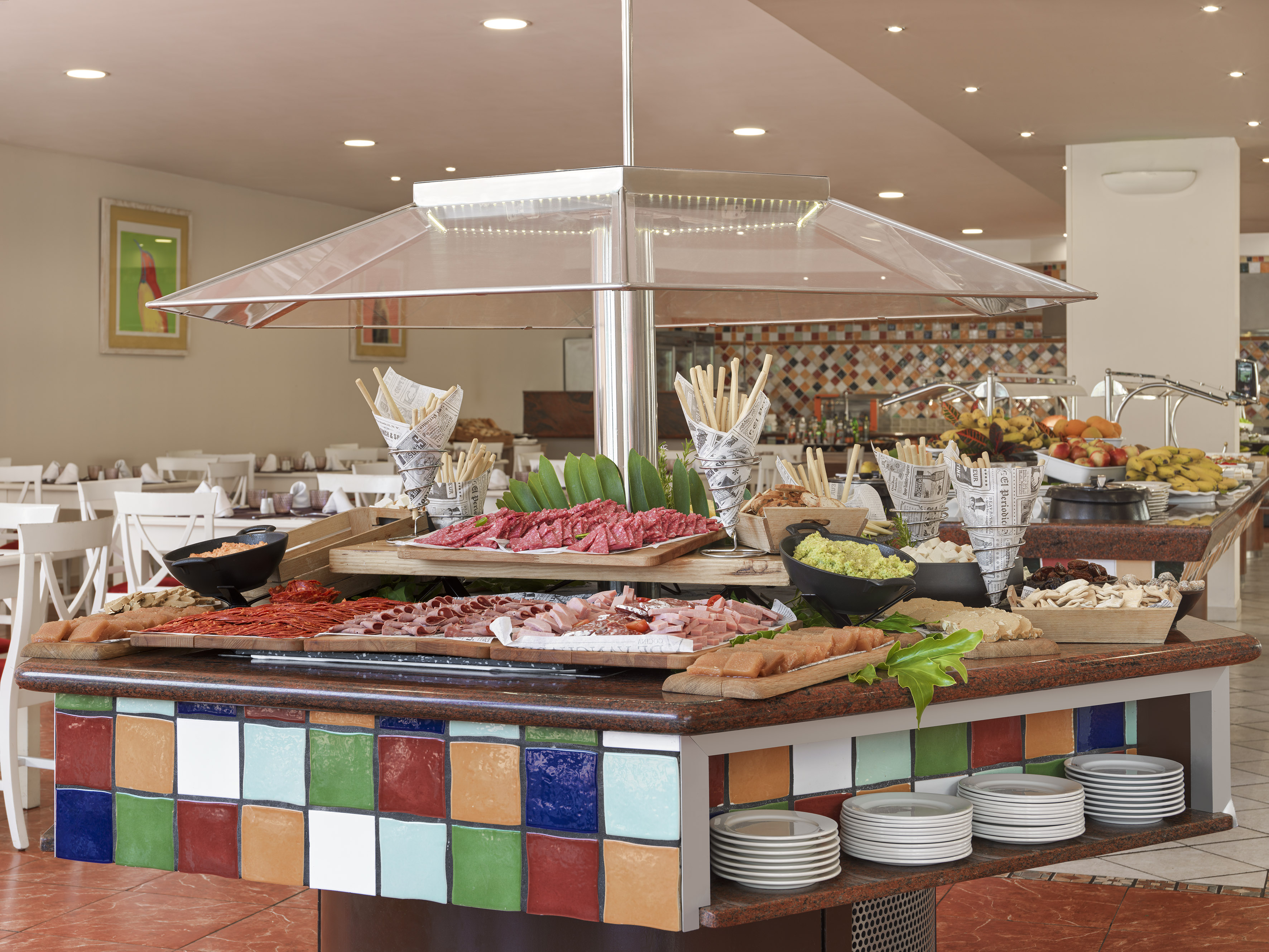 Colorful hotel buffet with cold meats, charcuterie, cheeses, and fresh fruit.