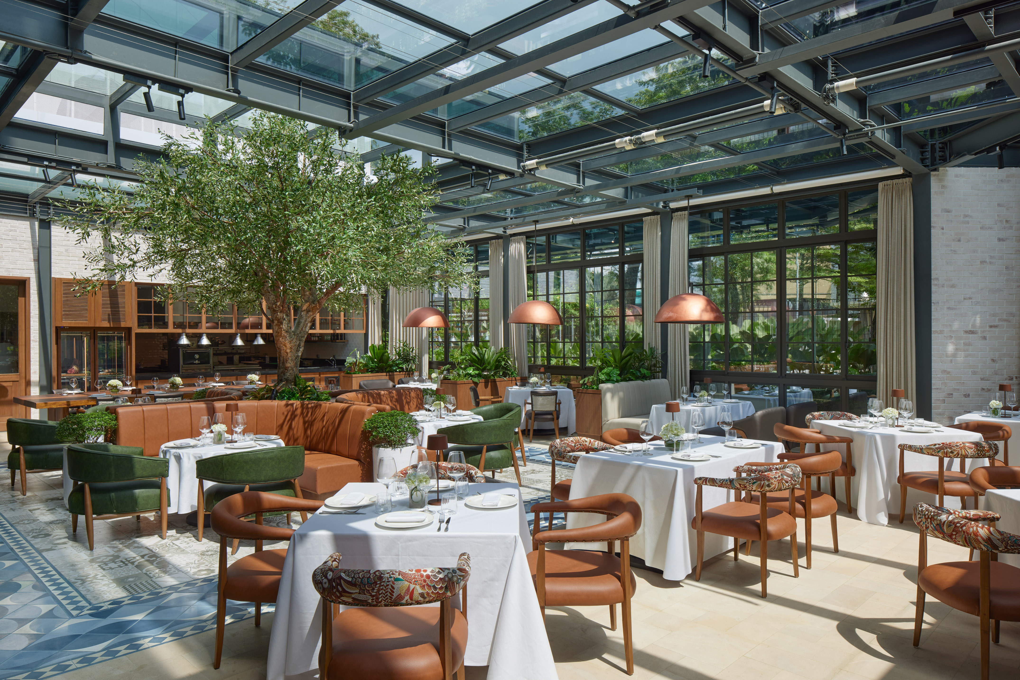 Luxury restaurant with glass roof, indoor tree, and elegant dining tables.