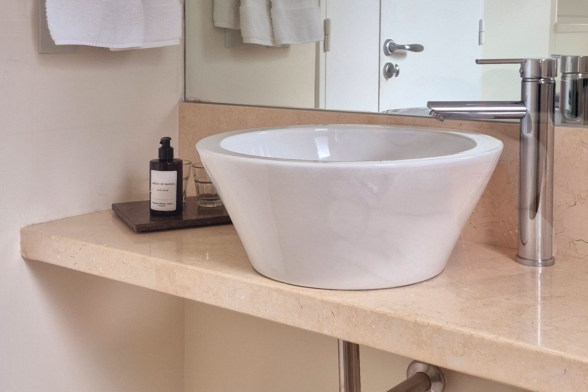 White vessel sink, chrome faucet on marble bathroom vanity.