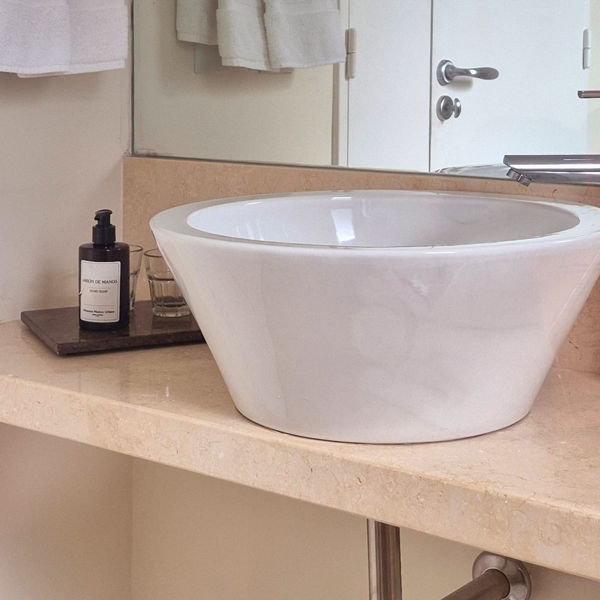 White vessel sink, chrome faucet on marble bathroom vanity.
