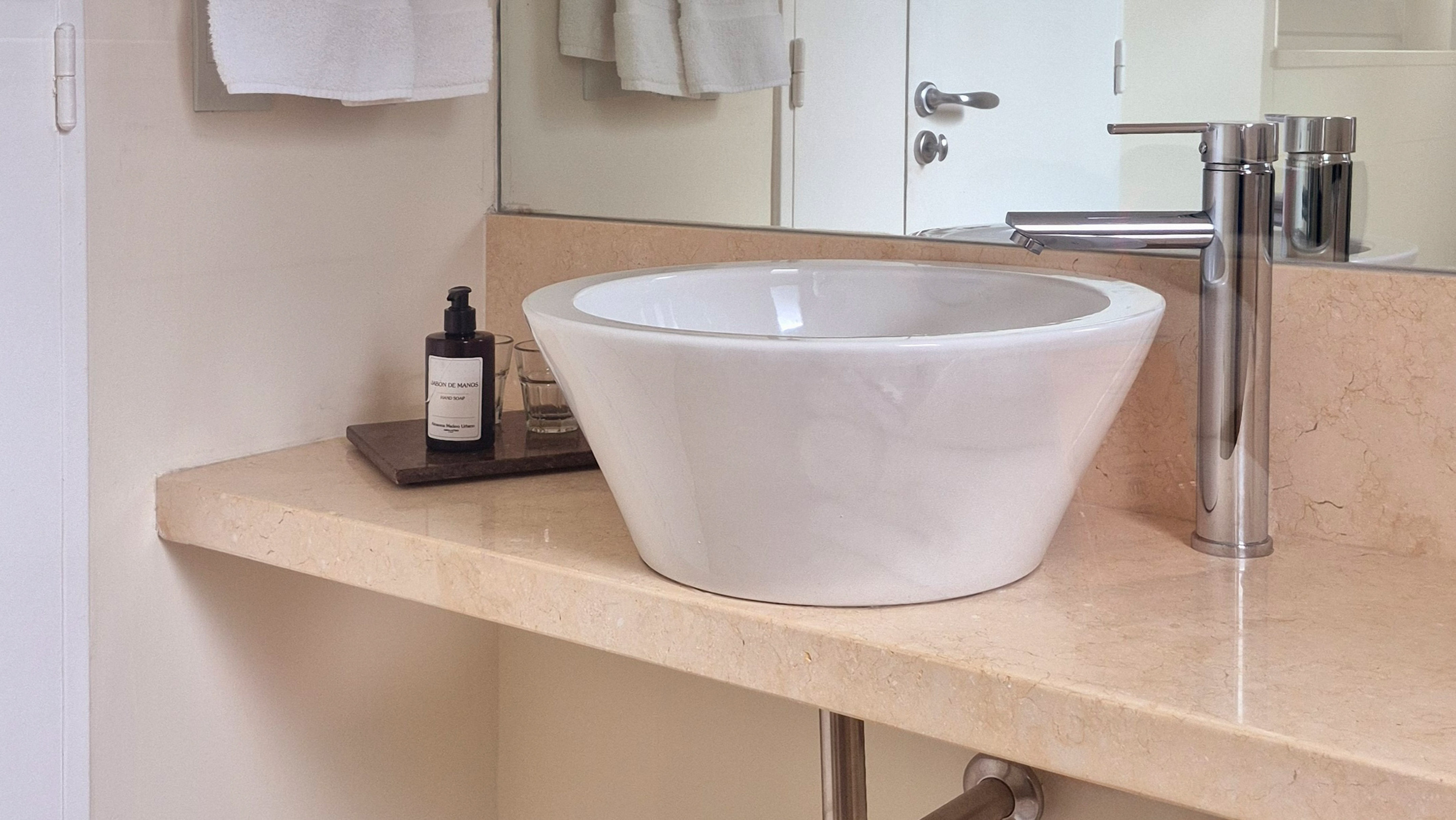 Modern bathroom vanity with white vessel sink, chrome faucet, and marble countertop.