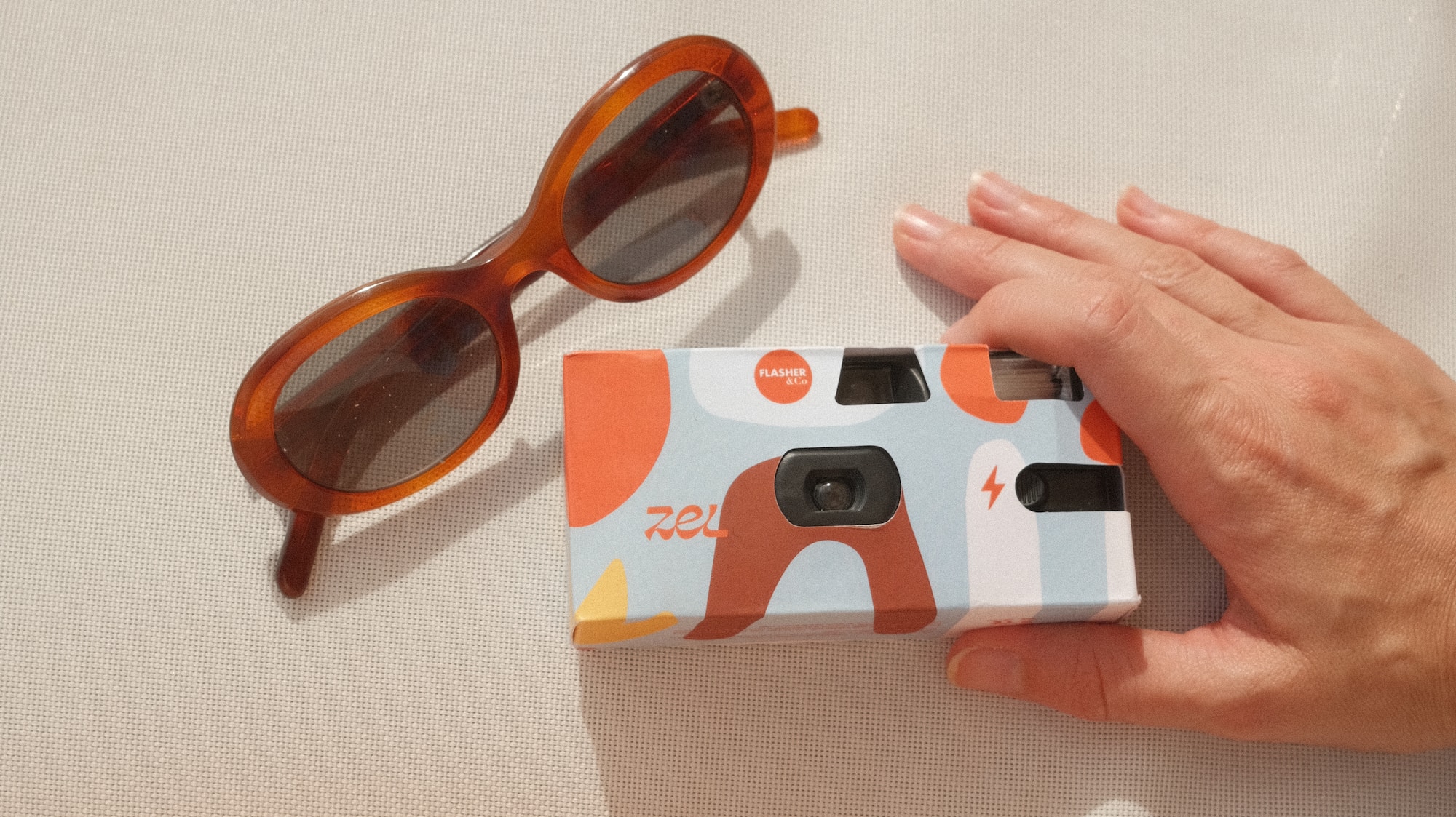 a hand holding a camera and sunglasses