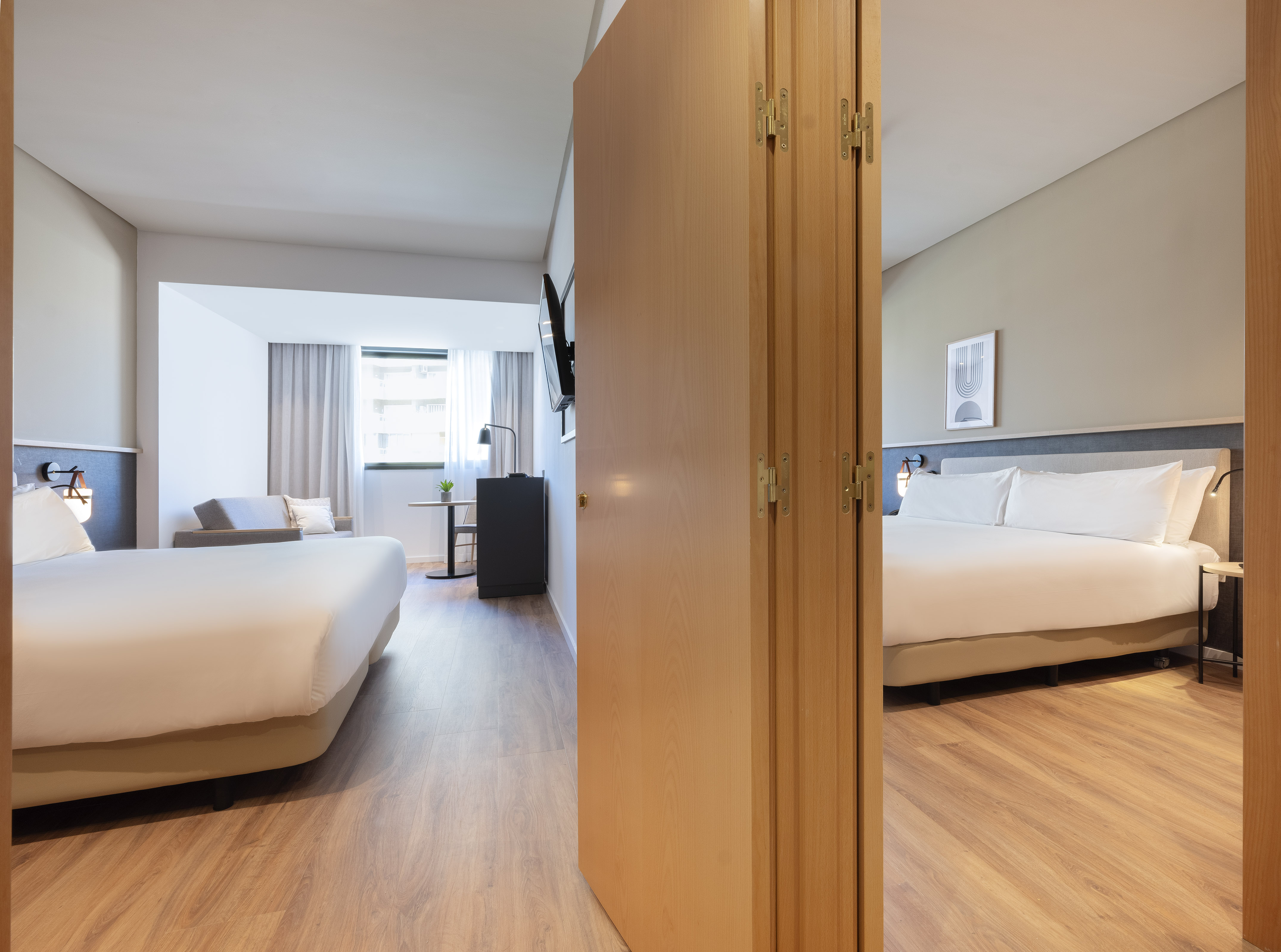 Hotel suite with two distinct sleeping areas, wood floor, and modern decor.