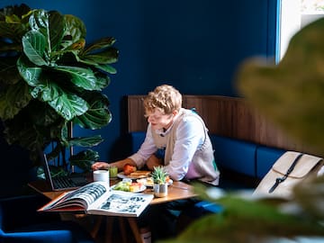 a woman sitting at a table with a laptop and food on it