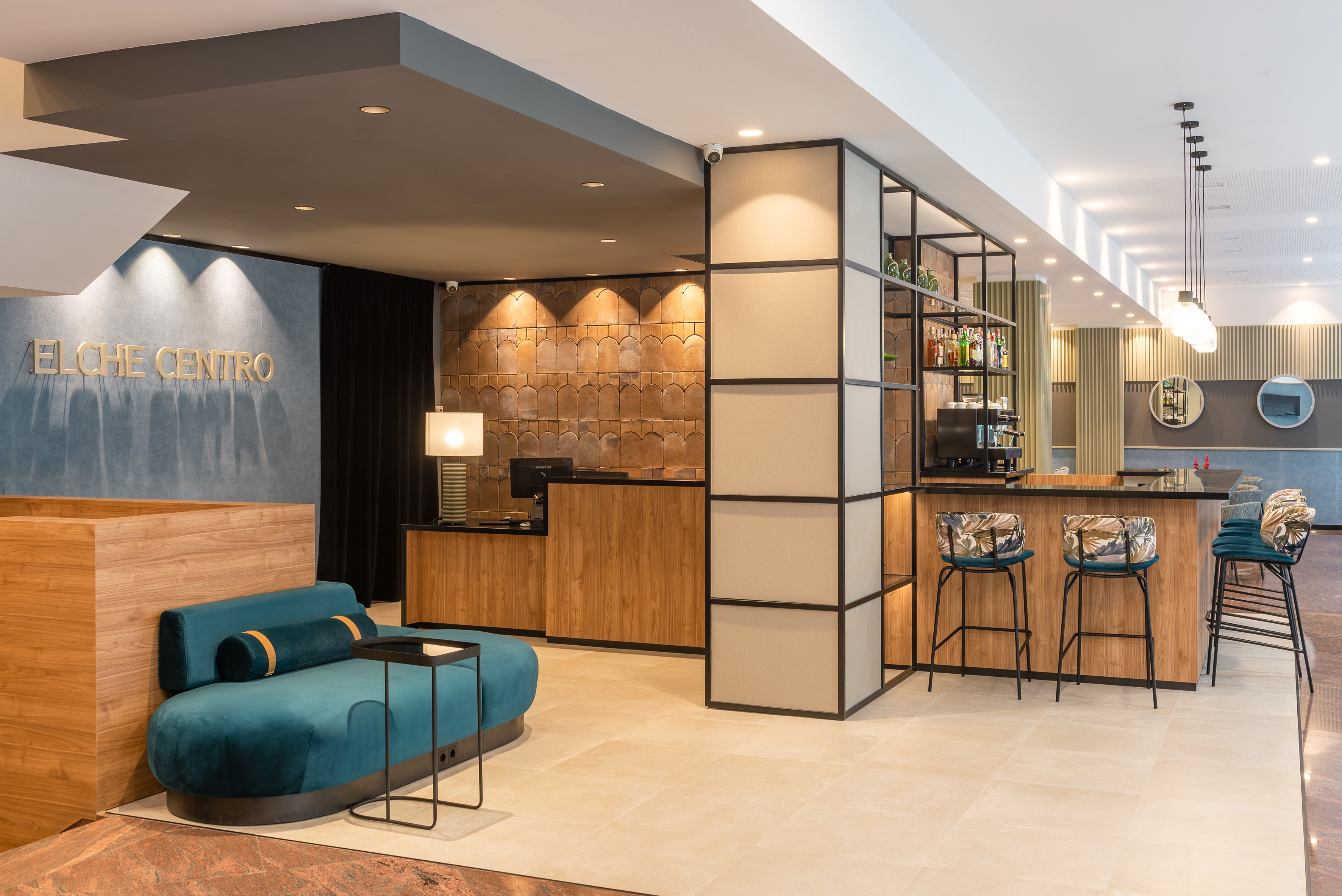 Elche Centro hotel lobby with modern reception, bar, and teal lounge sofa.