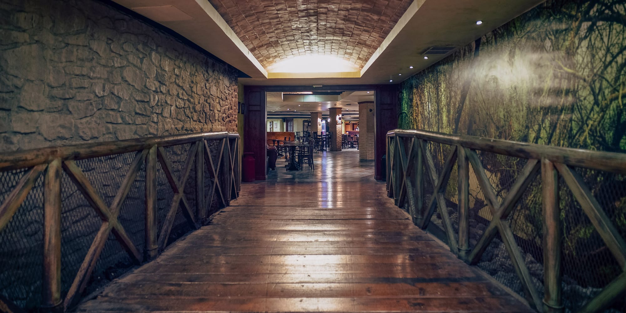 a wooden walkway with a stone wall and a stone wall