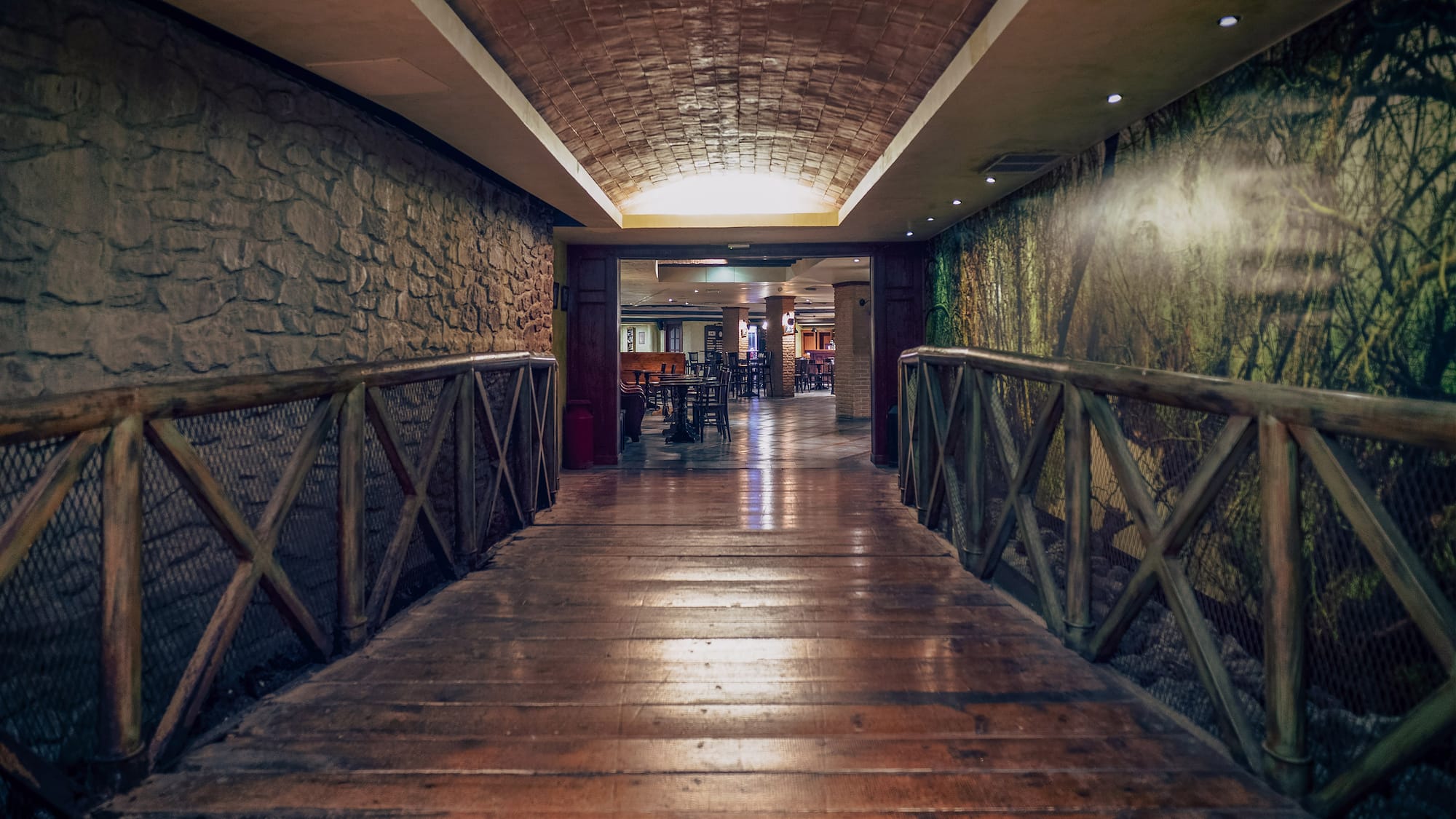 a wooden walkway with a stone wall and a stone wall