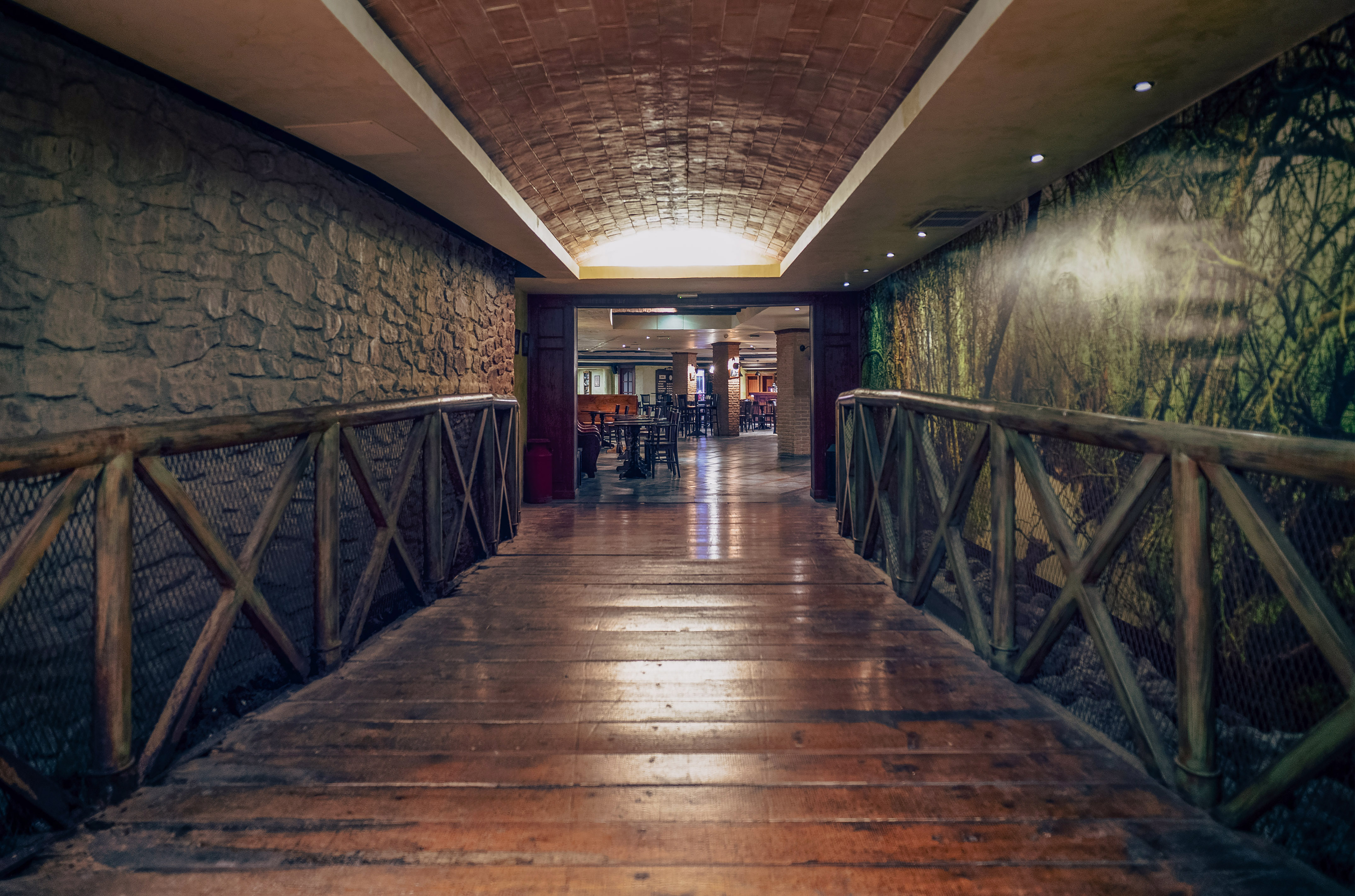a wooden walkway with a stone wall and a stone wall