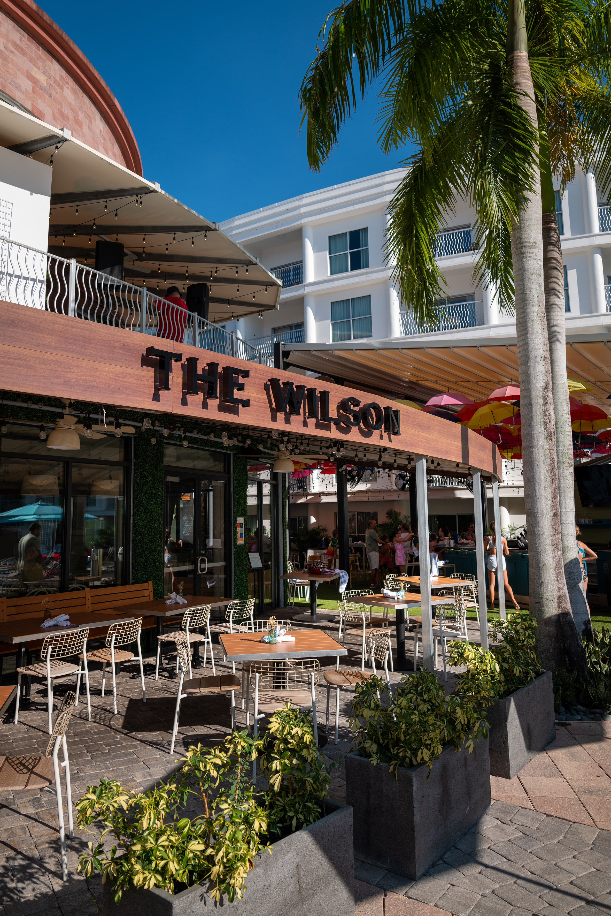 Sunny outdoor dining patio at The Wilson restaurant with palm trees. - The Wilson, Cozinha internacional - Meliá Orlando Celebration, Orlando