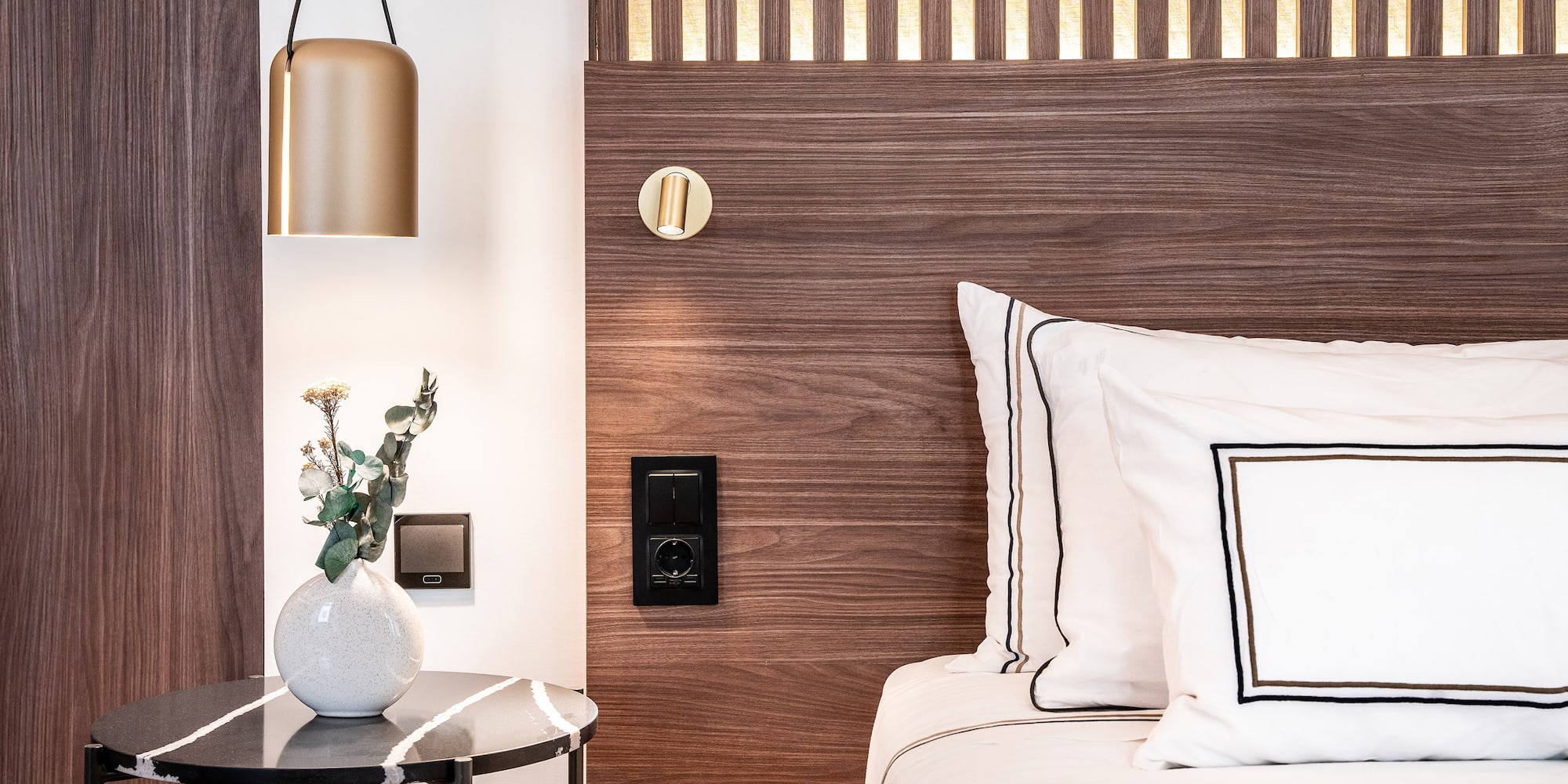 a bed with white pillows and a vase of flowers on a table