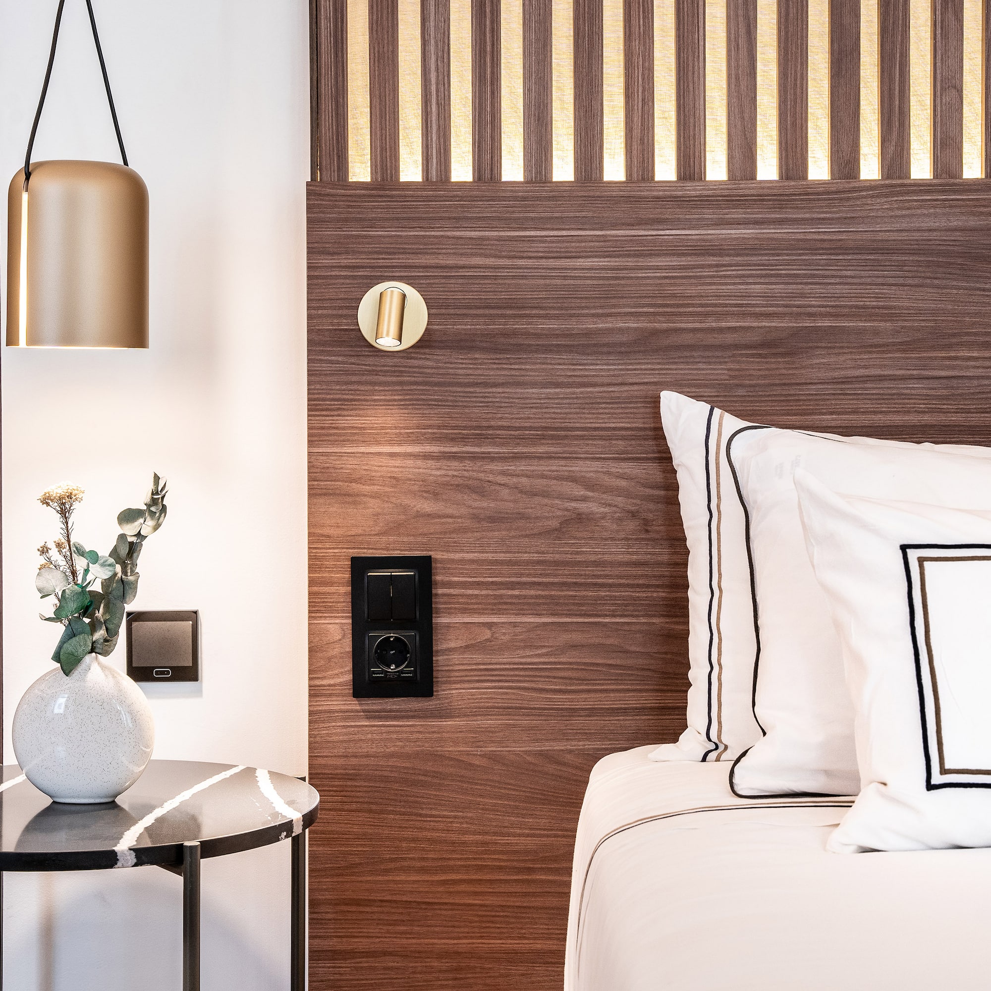 a bed with white pillows and a vase of flowers on a table