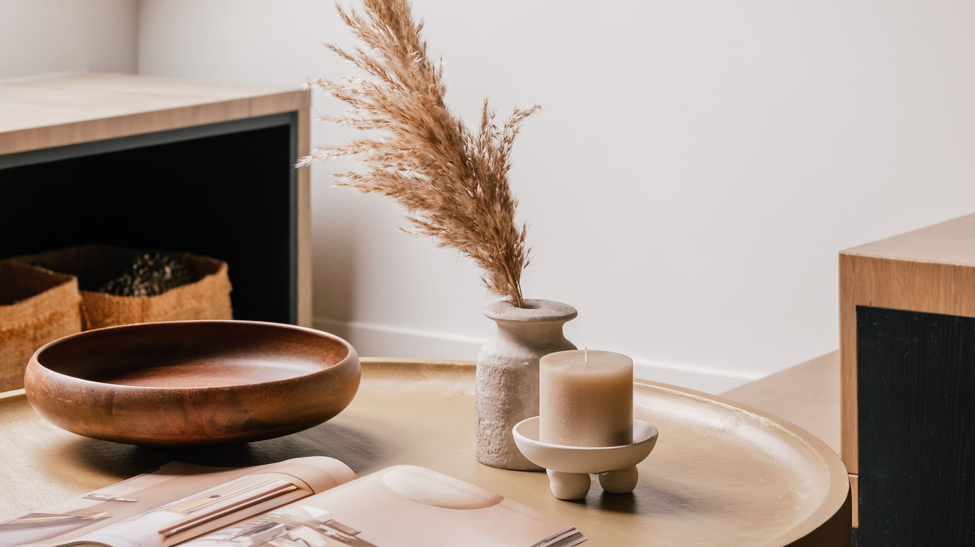 Modern living room with round coffee table, pampas grass, candle, and magazine.