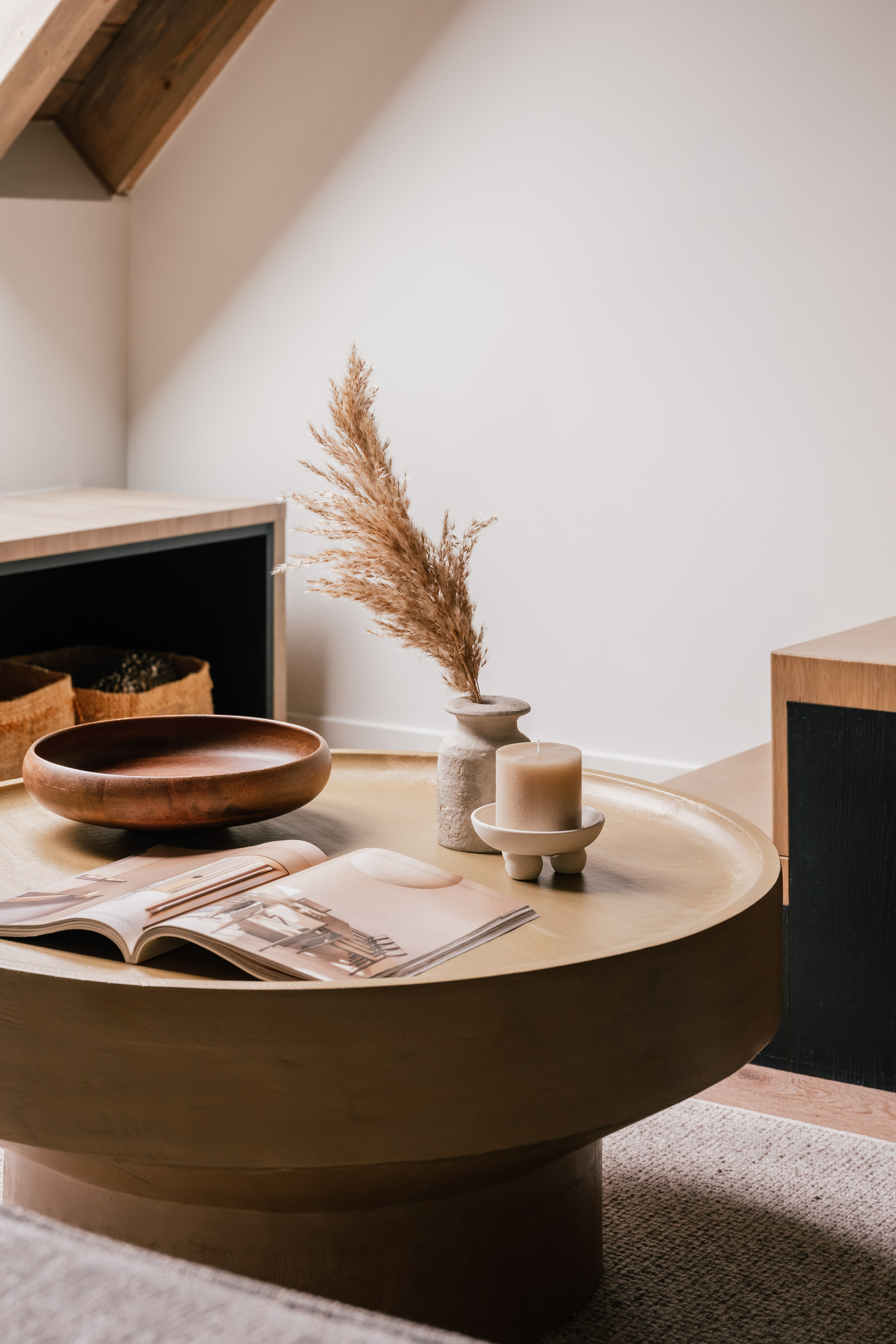 Modern living room with round coffee table, pampas grass, candle, and magazine.