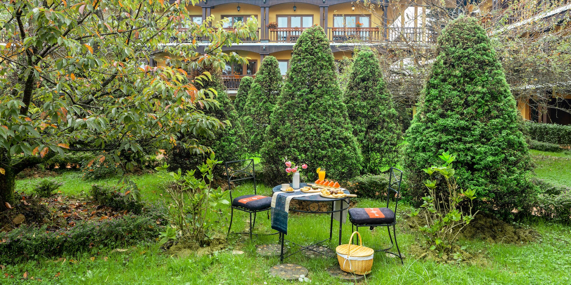 a table and chairs in a yard with a building in the background