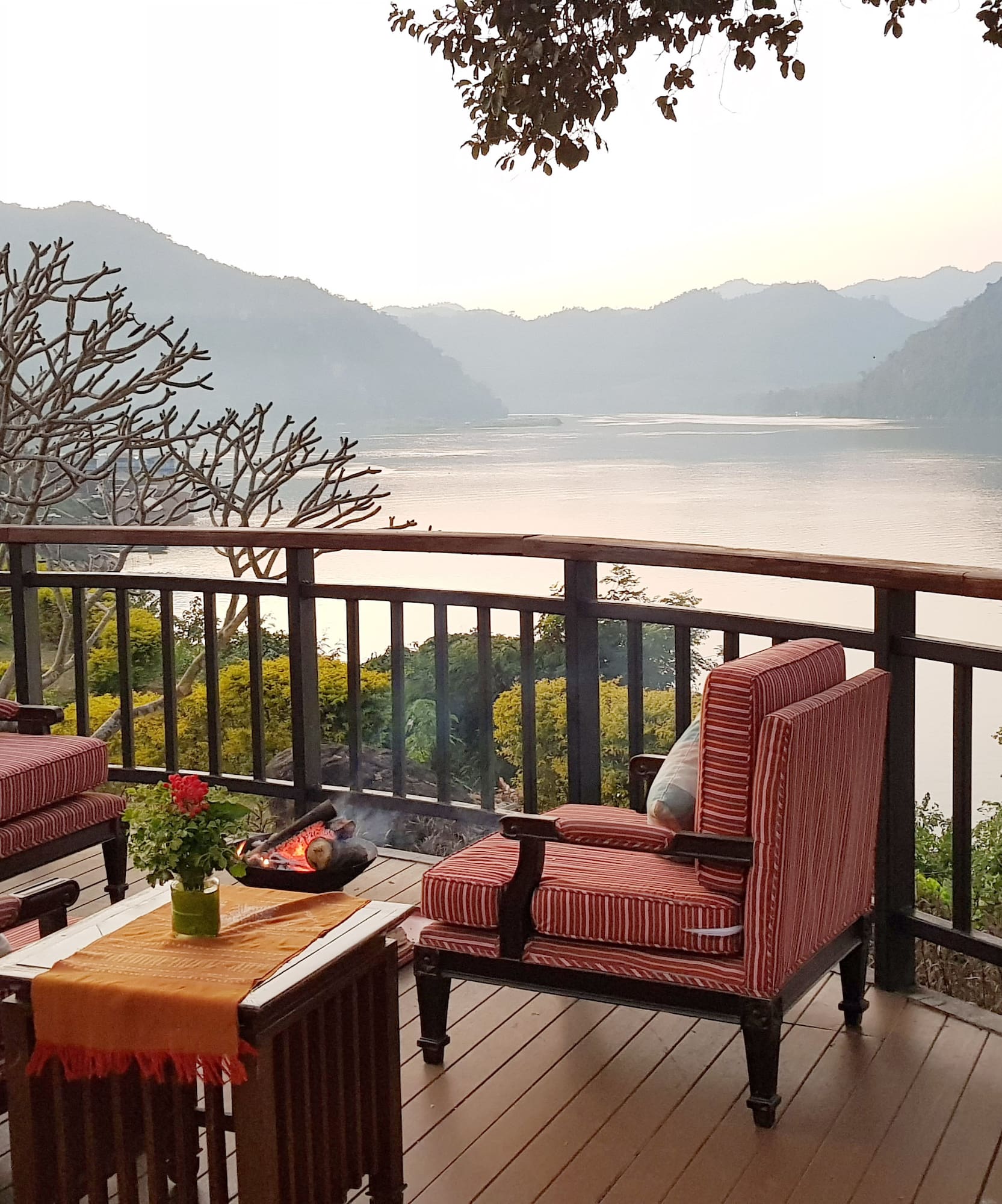 a deck with chairs and a fire pit overlooking a lake
