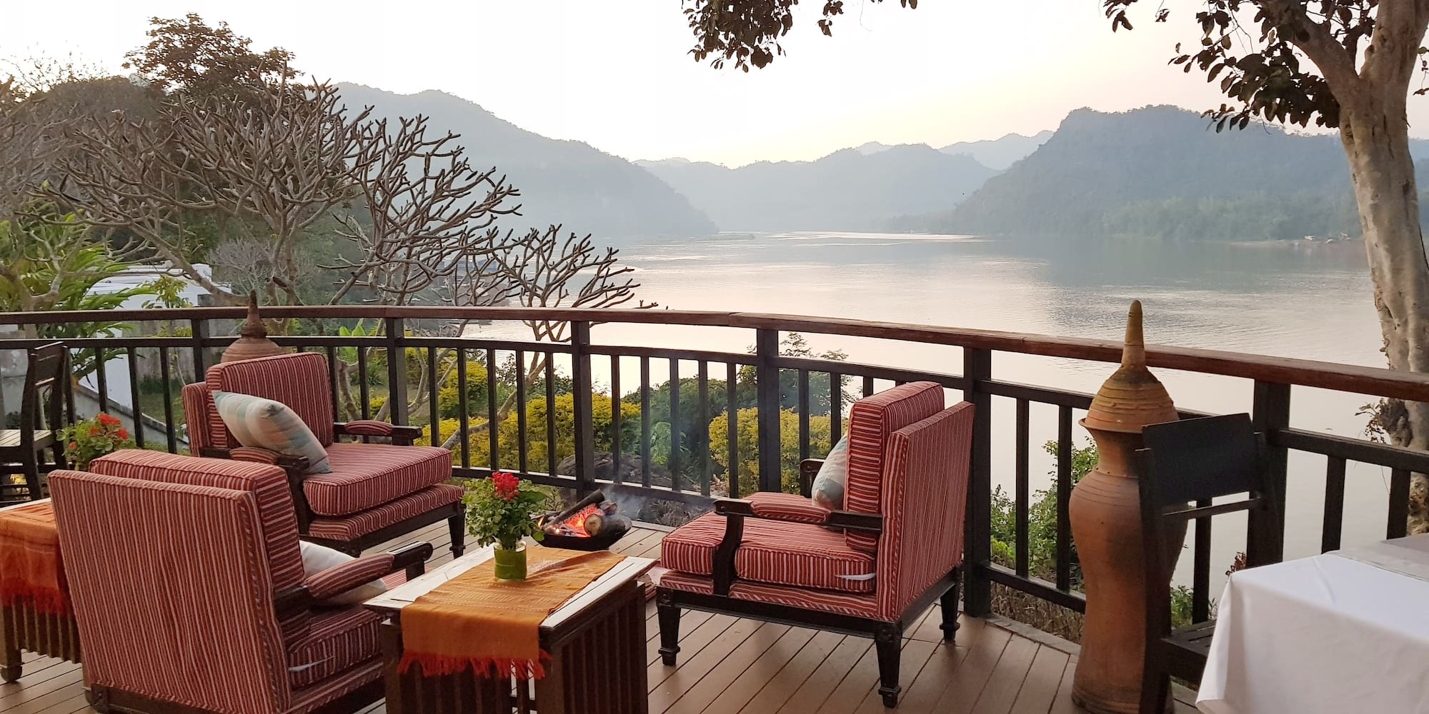 a deck with chairs and a fire pit overlooking a lake