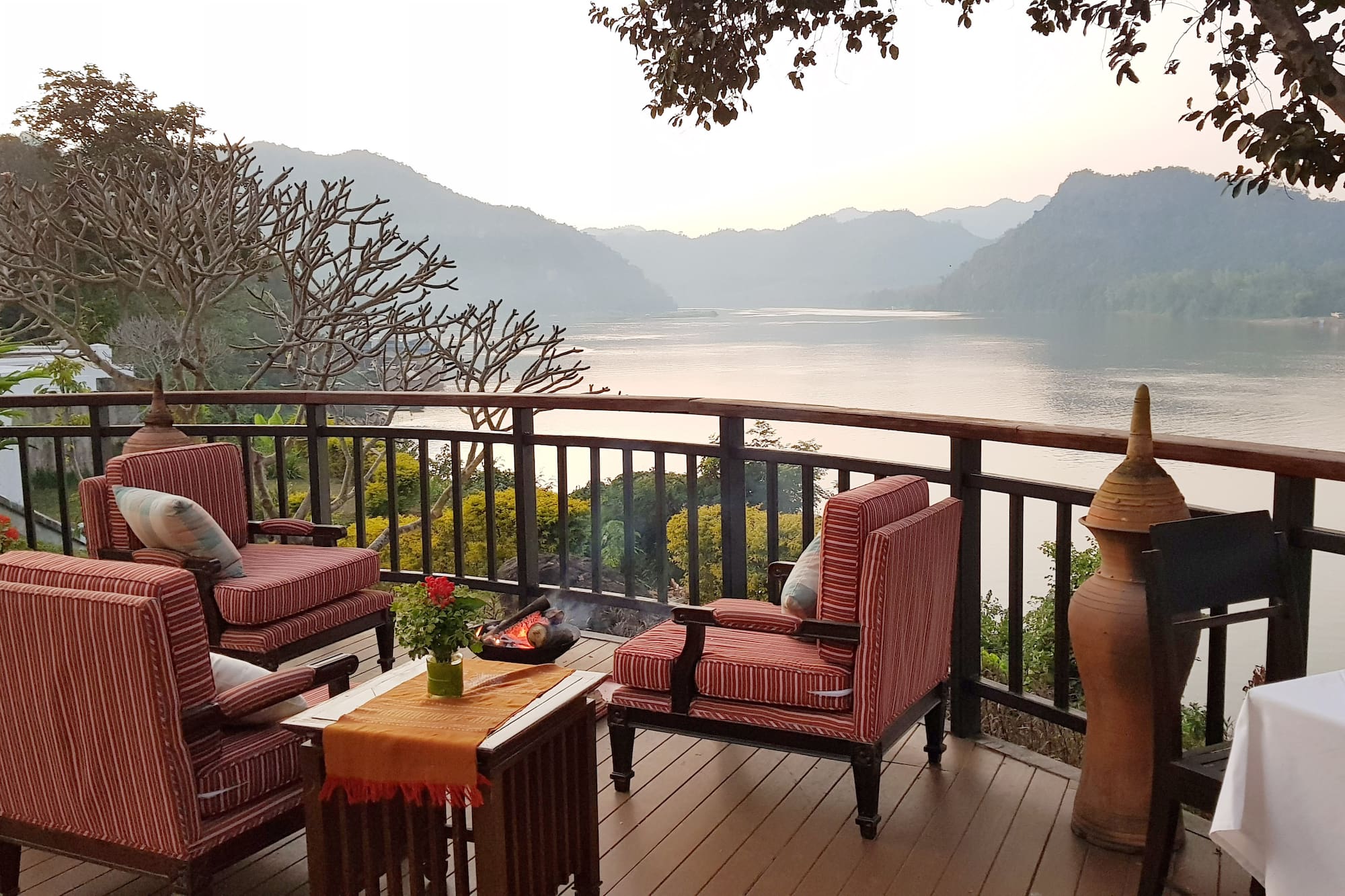 a deck with chairs and a fire pit overlooking a lake