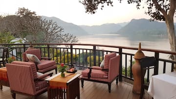 a deck with chairs and a fire pit overlooking a lake