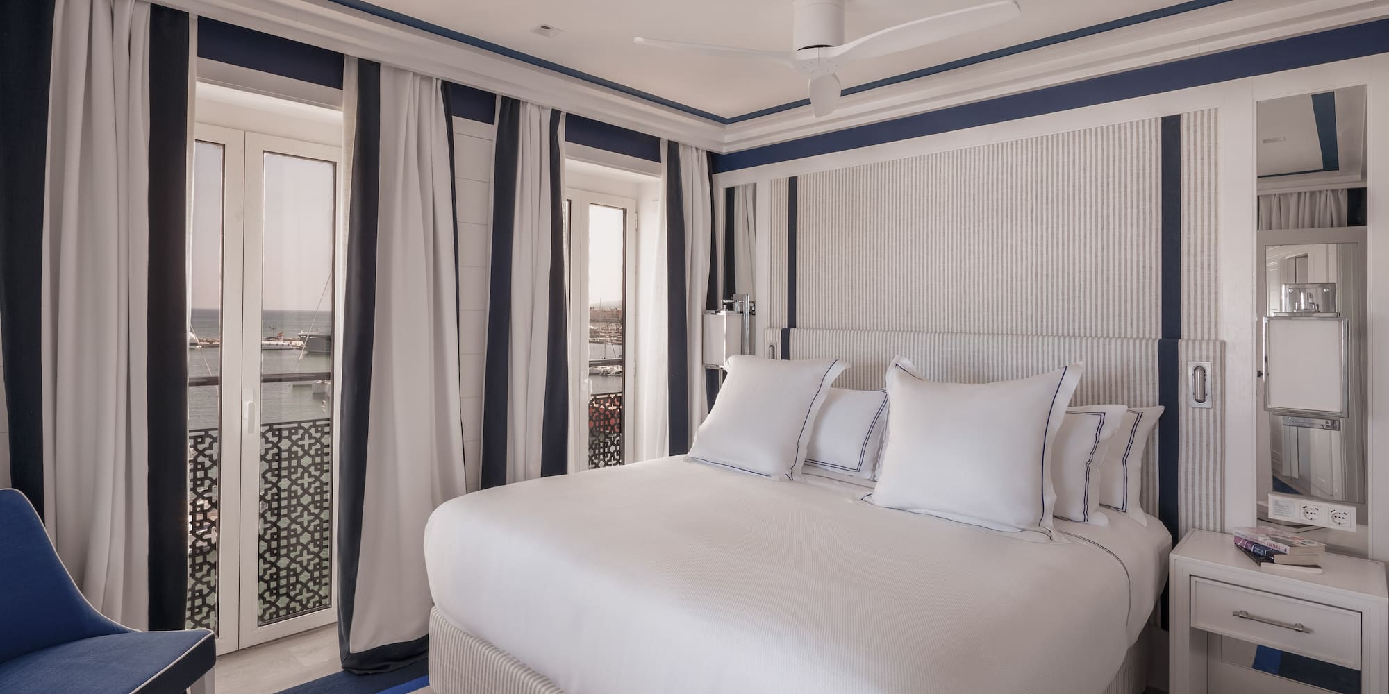 a bed with white pillows and a fan in a room with a window