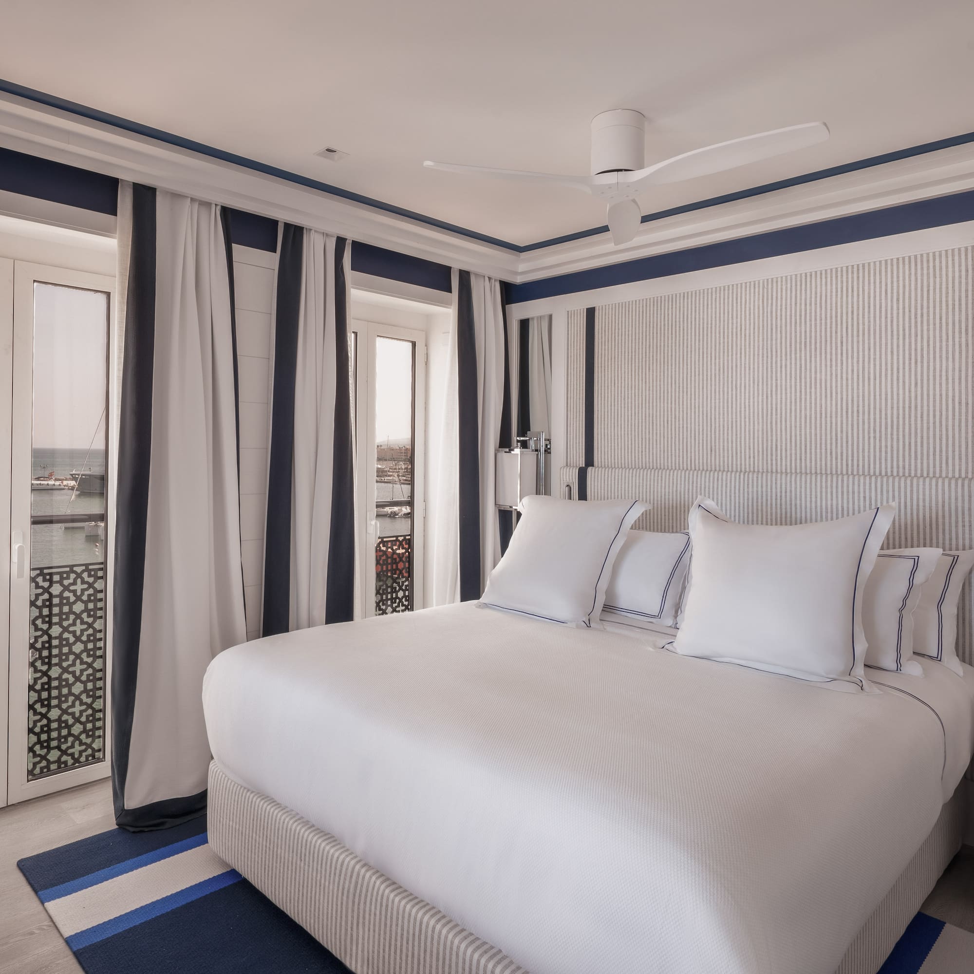 a bed with white pillows and a fan in a room with a window