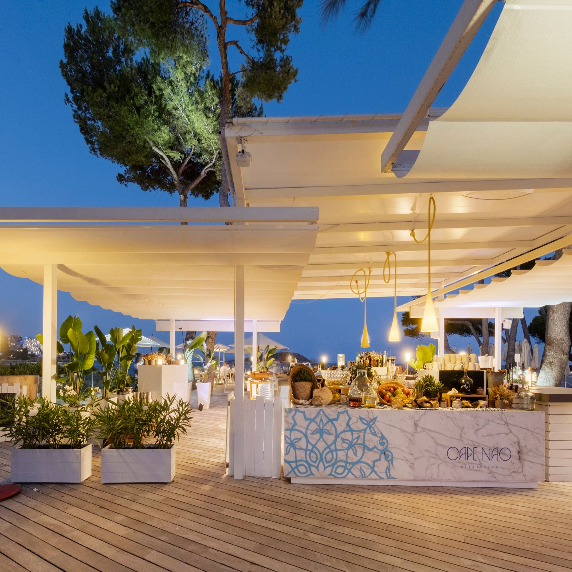 a white outdoor restaurant with a table and plants