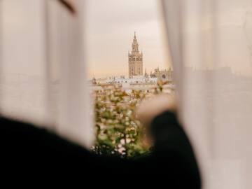 a person looking out a window with a tall building in the background