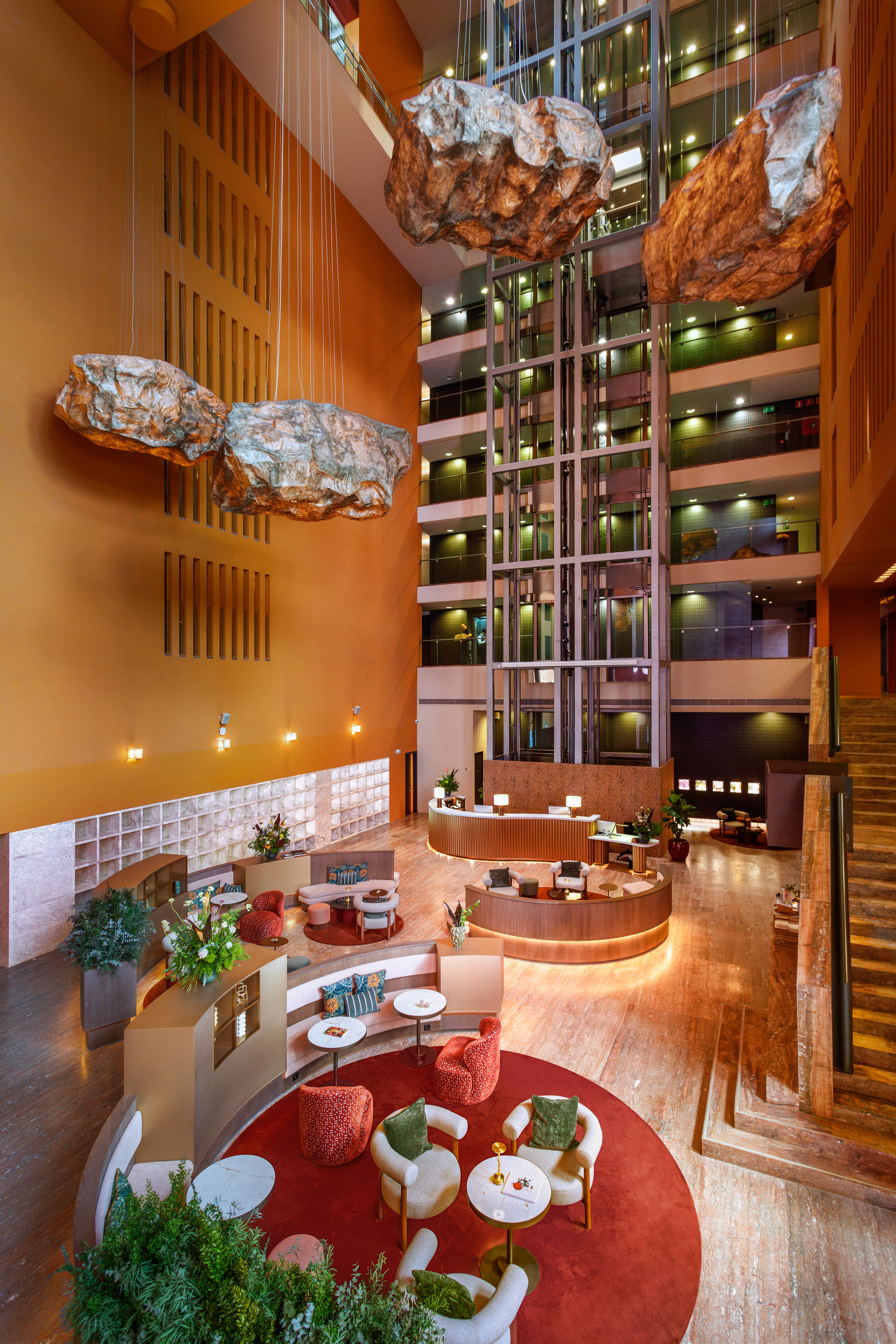 Hotel atrium with suspended rock decor, glass elevators, and stylish reception lounge.